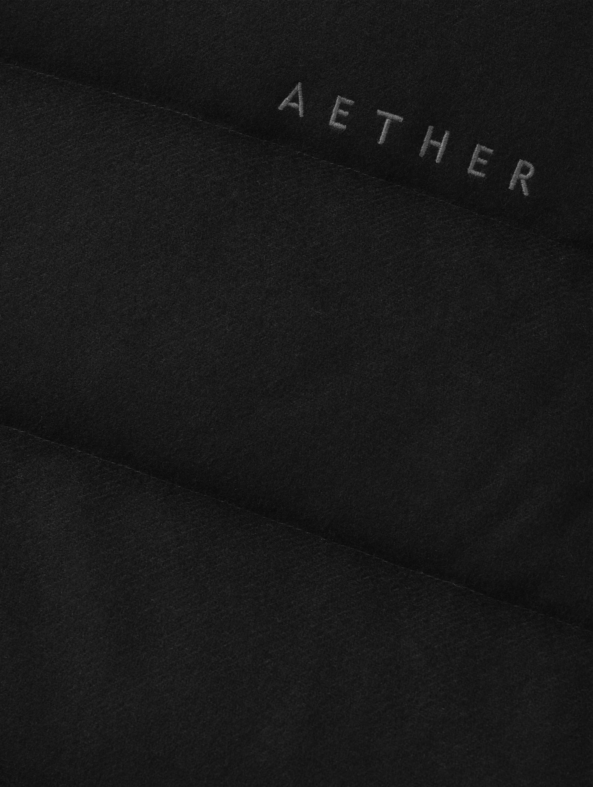 Closeup detailed view of the embroidered AETHER wordmark on the Channing Vest 2.0 in Onyx Black from AETHER Apparel.