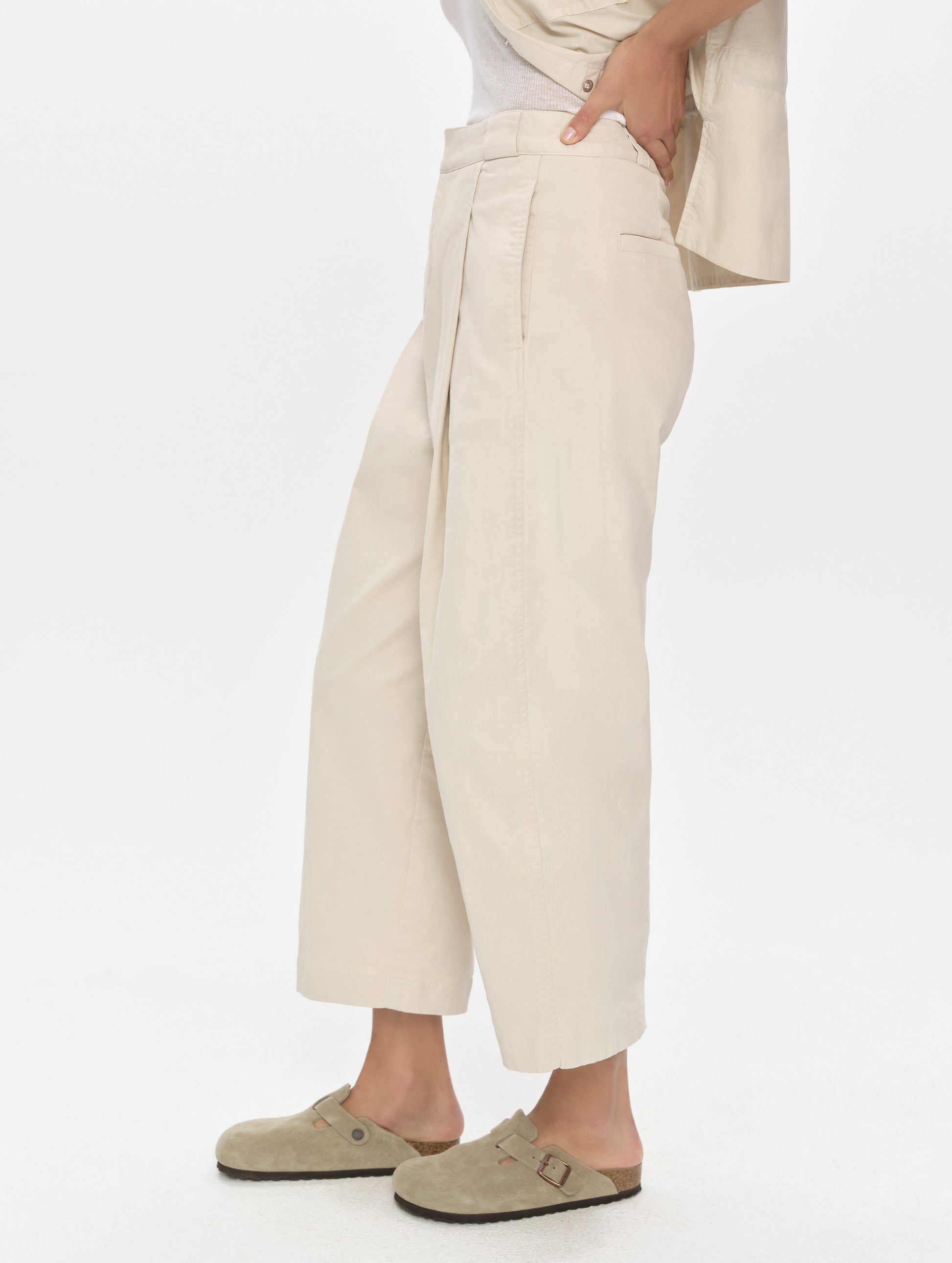 Side profile, lower-body view of woman wearing the Dune Pant in Bone from AETHER Apparel.