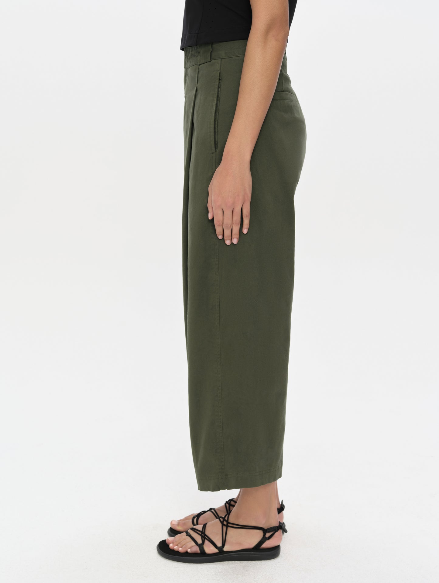 Side profile, lower-body view of woman wearing the Dune Pant in Forest Green from AETHER Apparel.