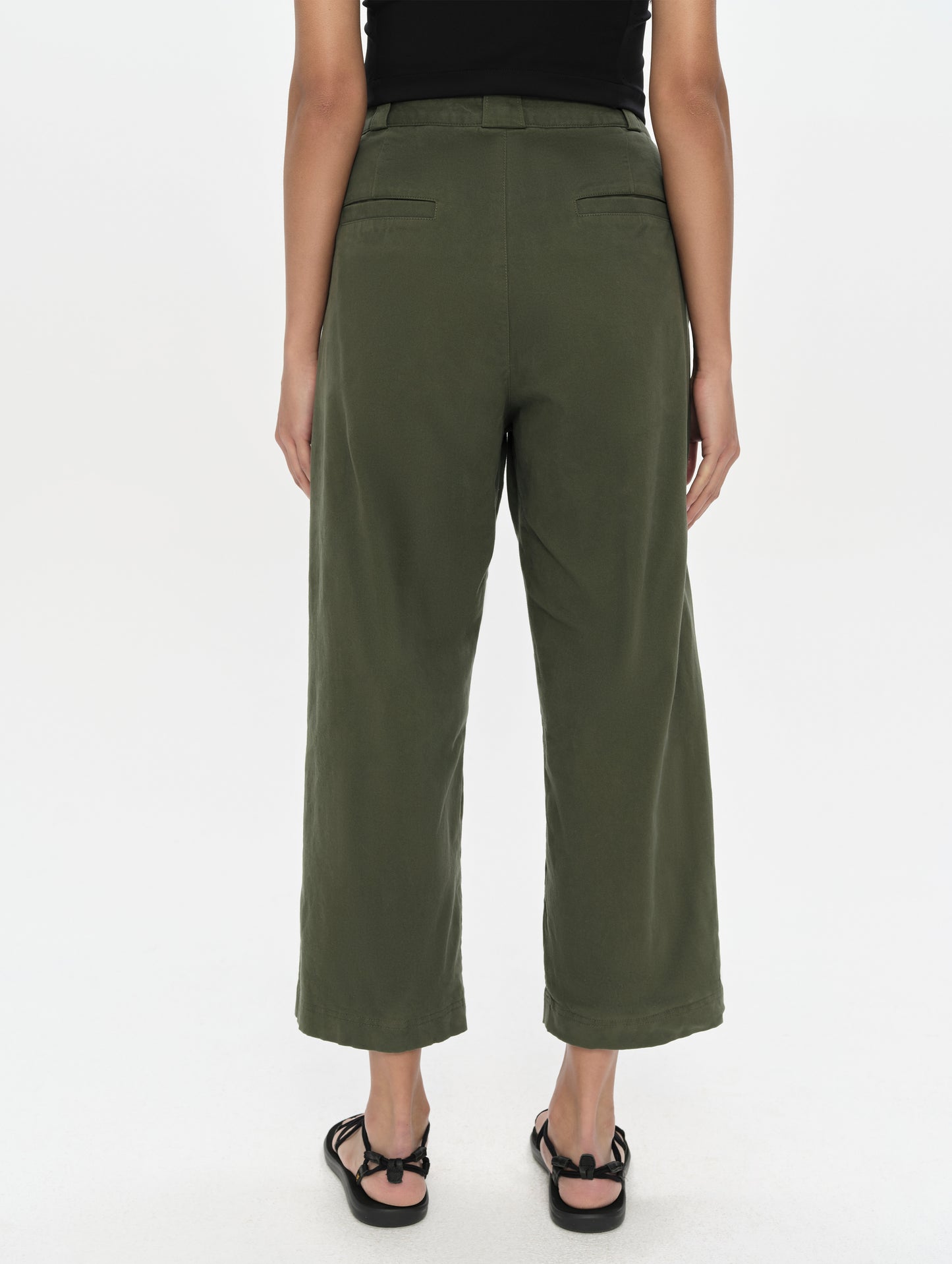 Rear, lower-body view of woman wearing the Dune Pant in Forest Green from AETHER Apparel.