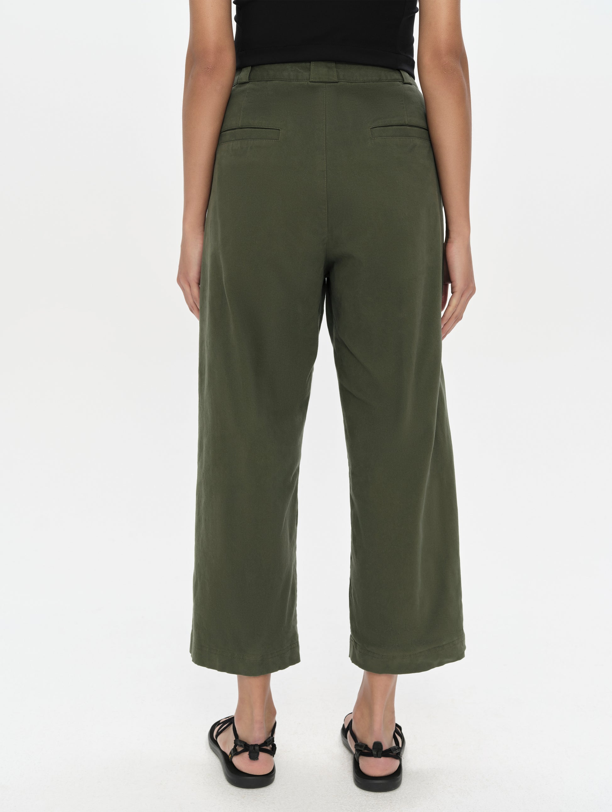 Rear, lower-body view of woman wearing the Dune Pant in Forest Green from AETHER Apparel.