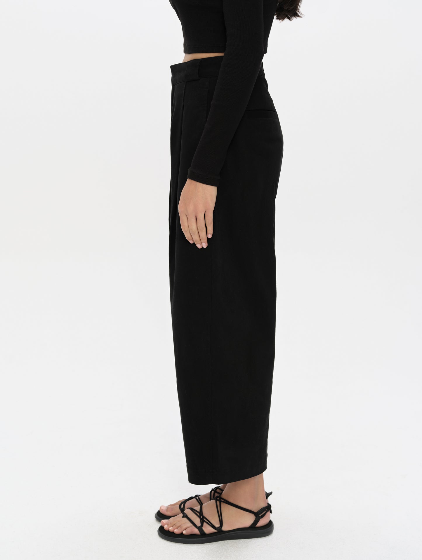 Side profile, lower-body view of woman wearing the Dune Pant in Onyx Black from AETHER Apparel.