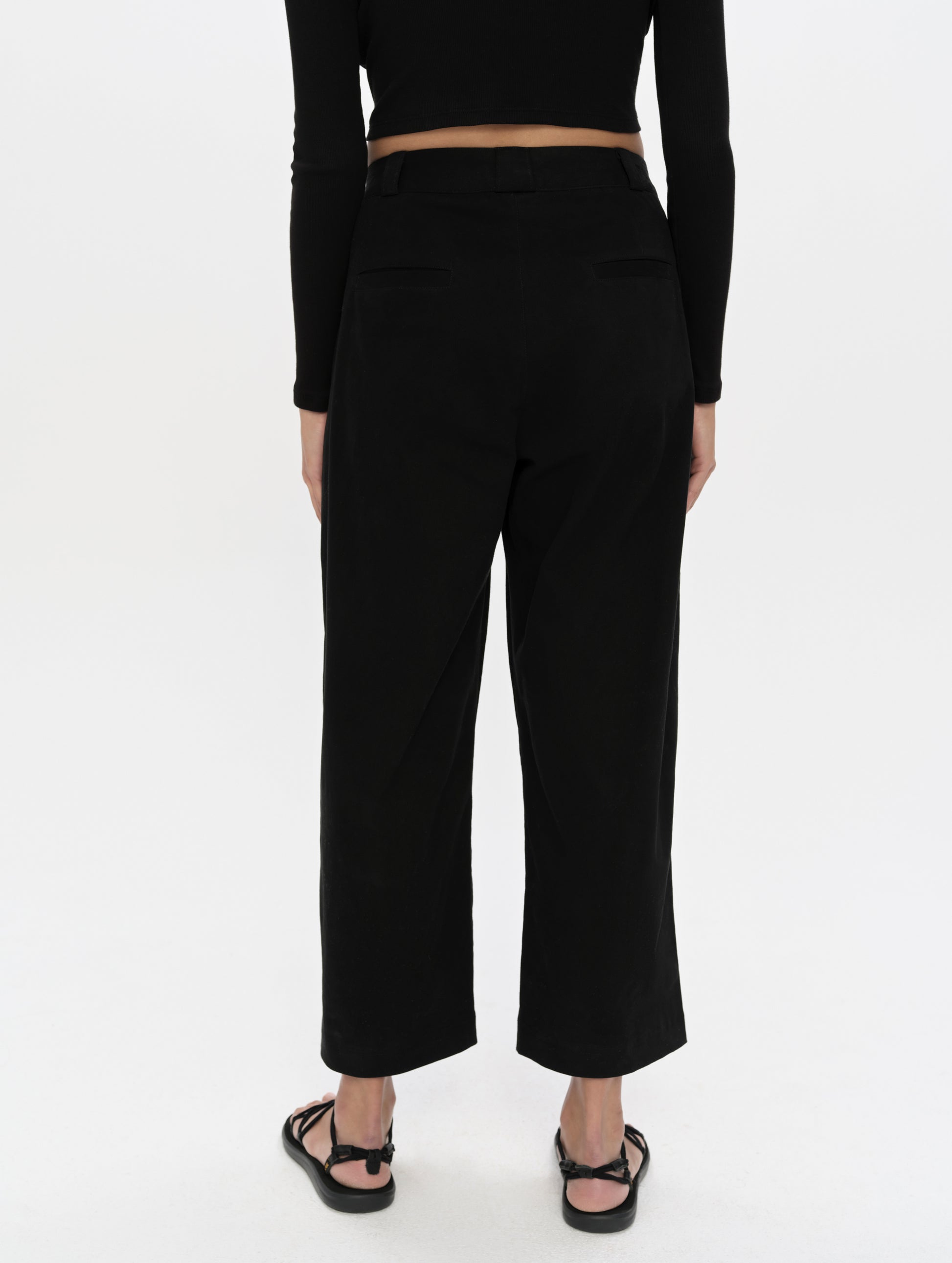 Rear, lower-body view of woman wearing the Dune Pant in Onyx Black from AETHER Apparel.
