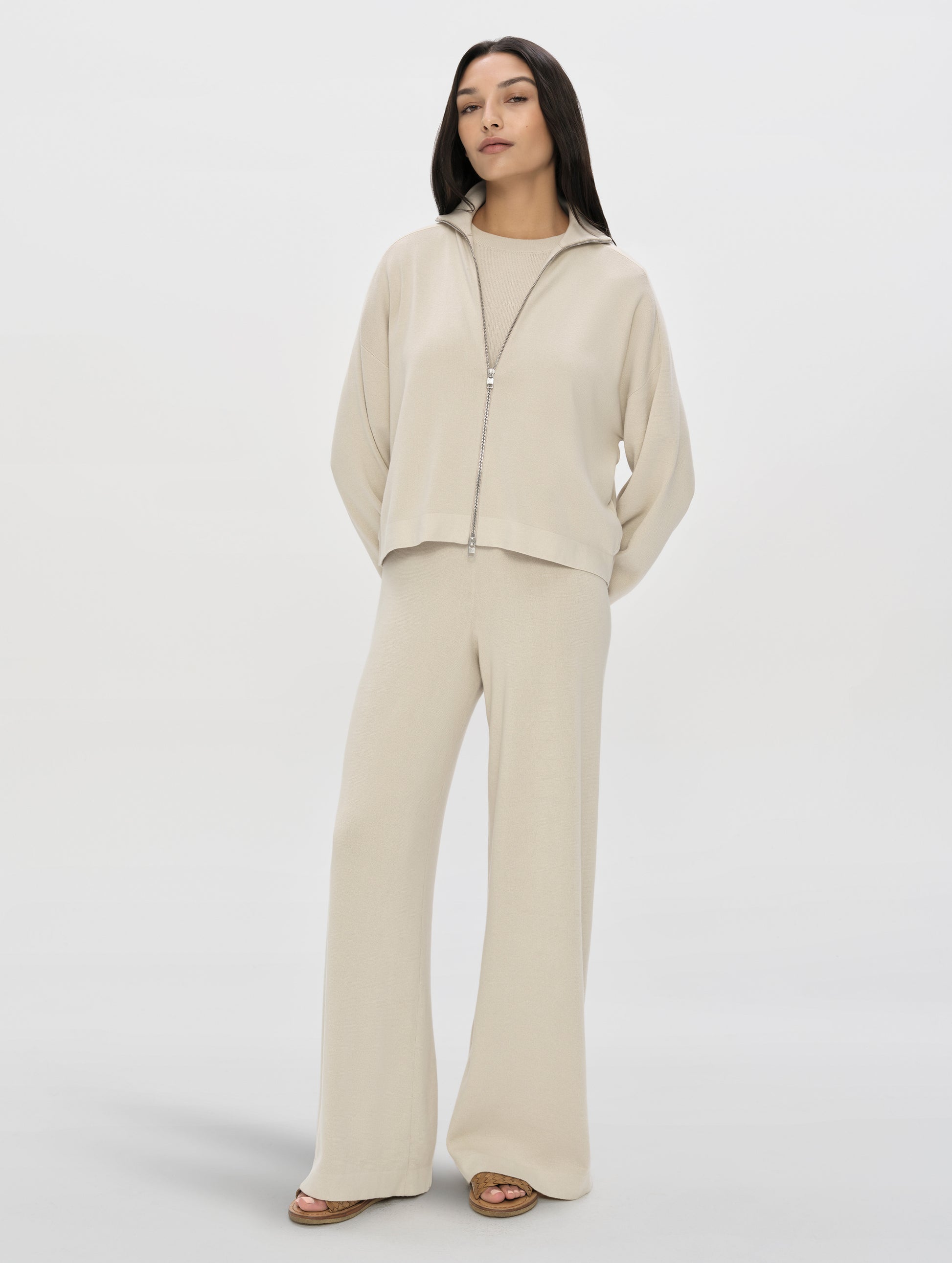 Front, full-body view of woman wearing the Eliana Full-ZIp Sweater in Bone from AETHER Apparel.