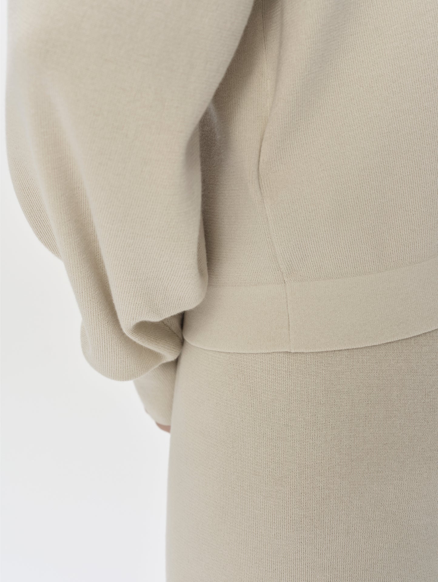 Closeup detailed view of the bottom hem on the Eliana Full-ZIp Sweater in Bone from AETHER Apparel.