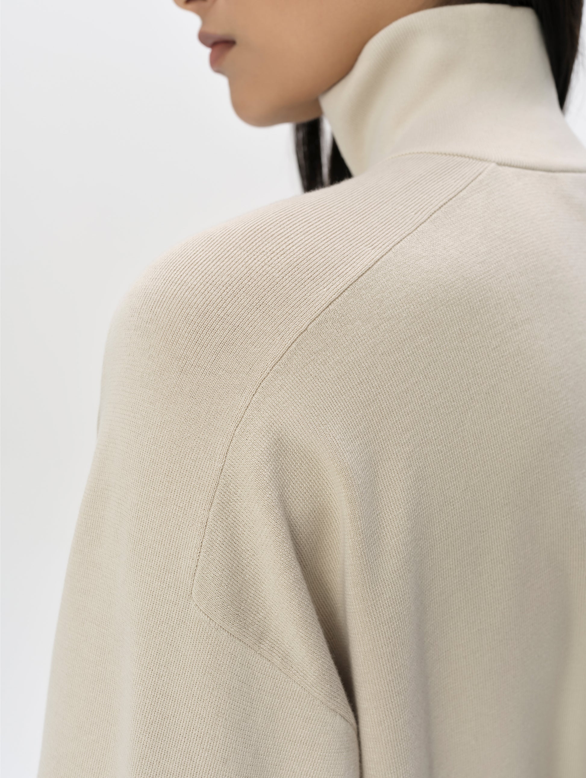 Closeup detailed view of the shoulder and collar on the Eliana Full-ZIp Sweater in Bone from AETHER Apparel.