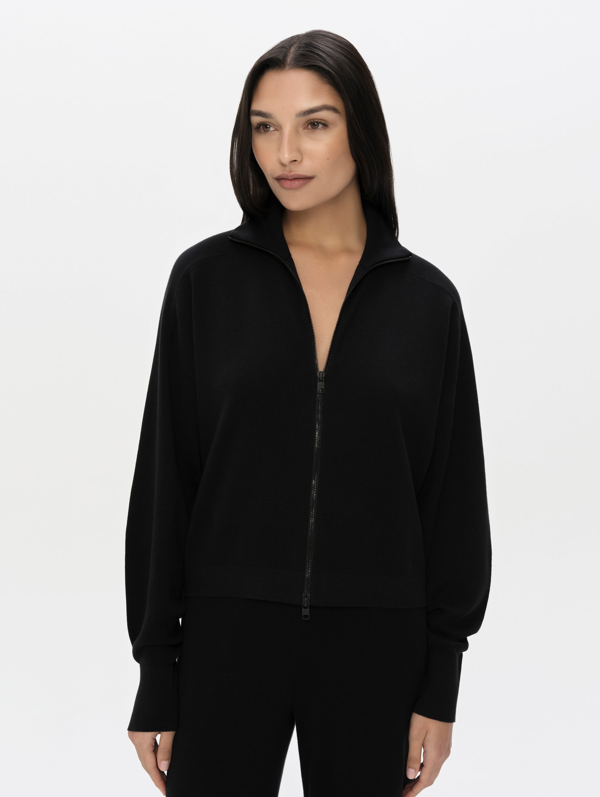 Front, upper-body view of woman wearing the Eliana Full-ZIp Sweater in Onyx Black from AETHER Apparel.