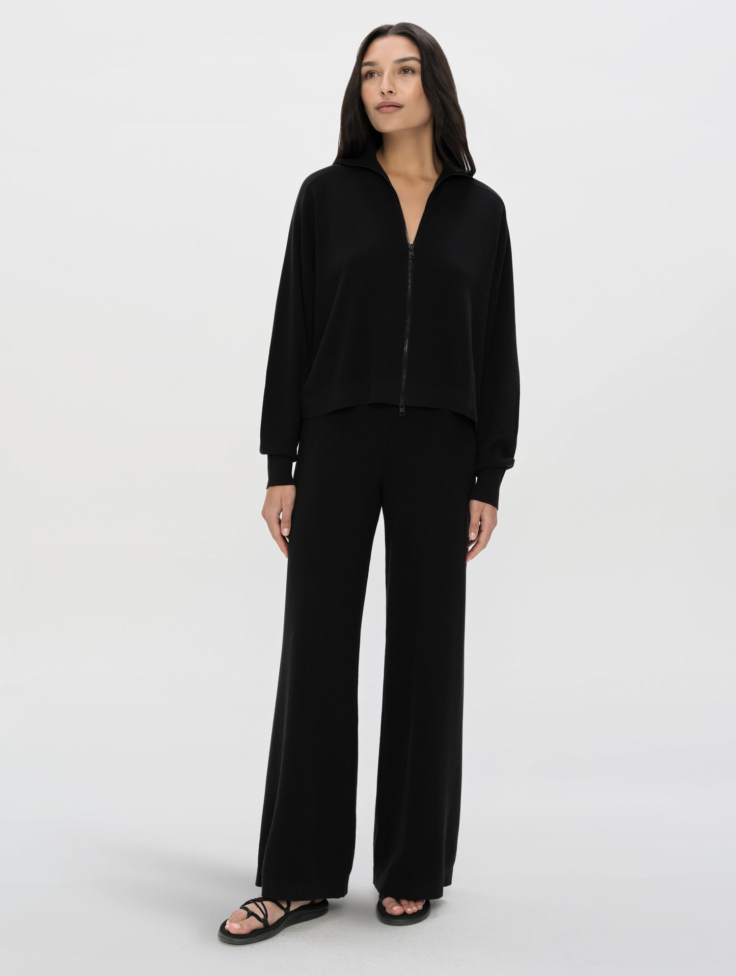 Front, full-body view of woman wearing the Eliana Full-ZIp Sweater in Onyx Black from AETHER Apparel.