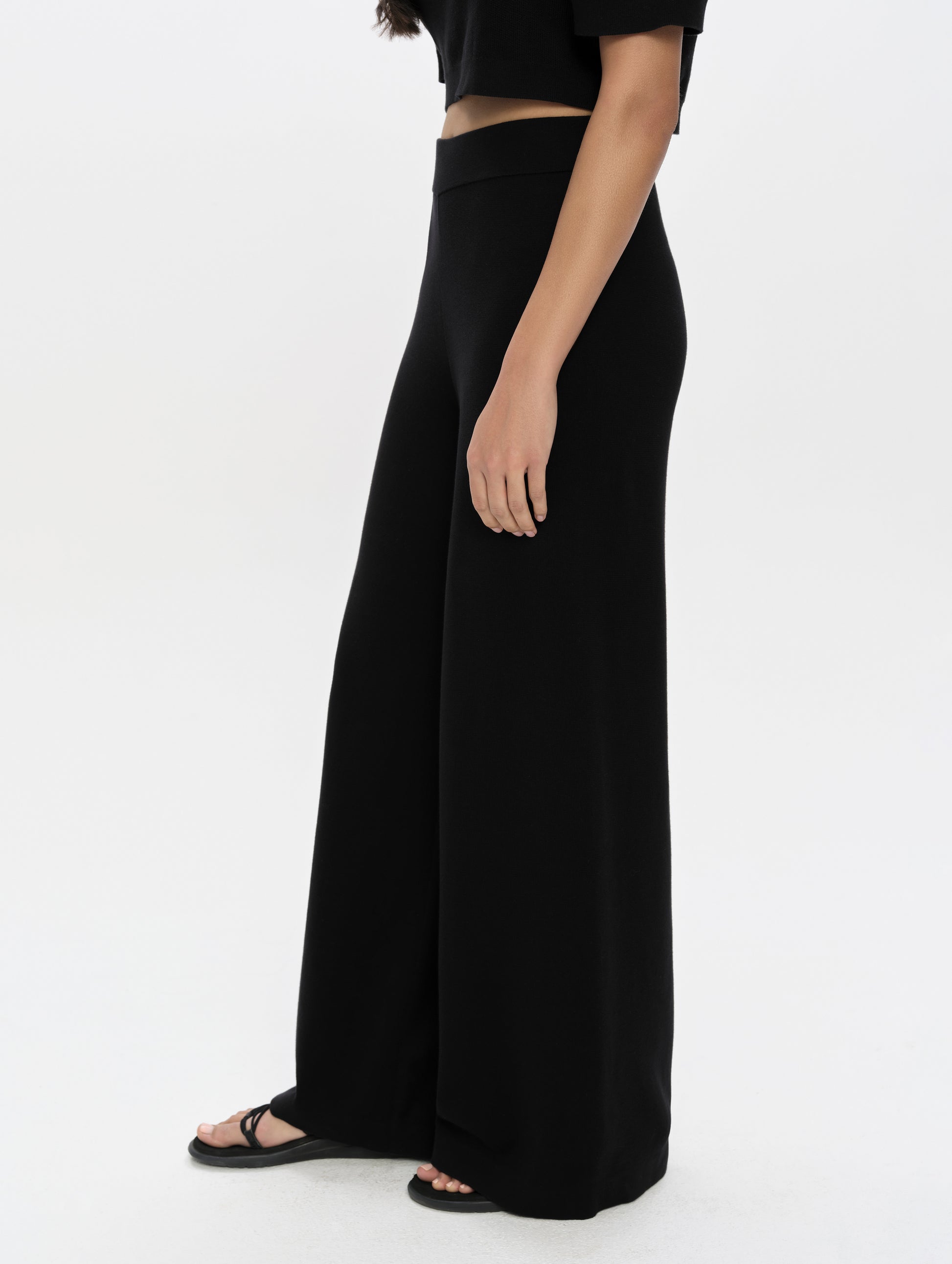 Side profile, lower-body view of woman wearing the Eliana Sweater Pant in Onyx Black from AETHER Apparel.