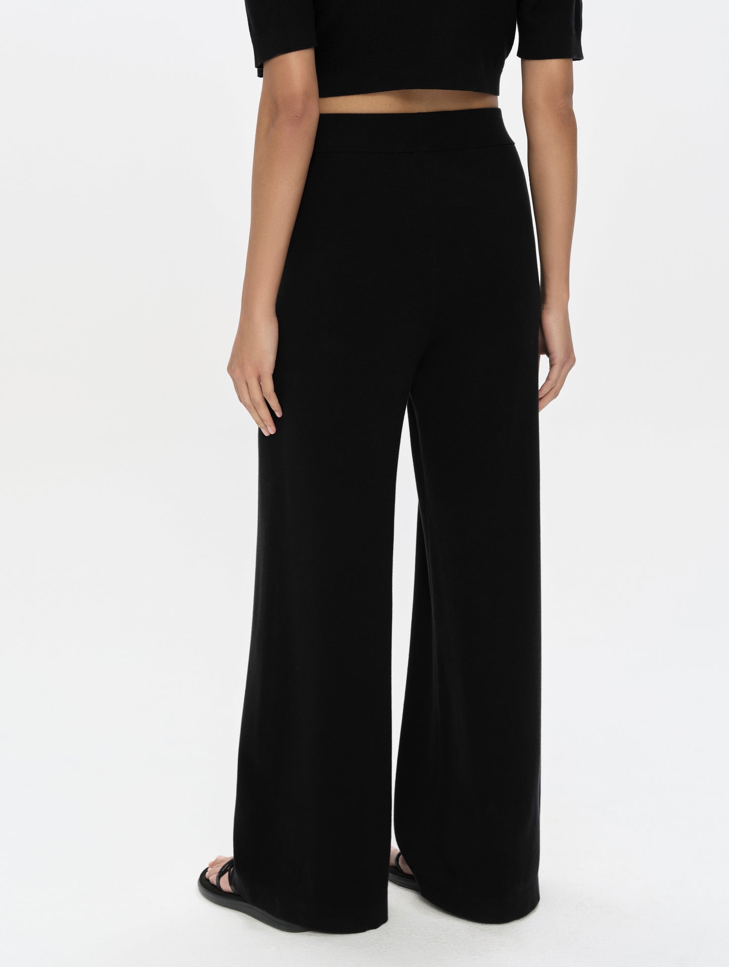 Rear, lower-body view of woman wearing the Eliana Sweater Pant in Onyx Black from AETHER Apparel.