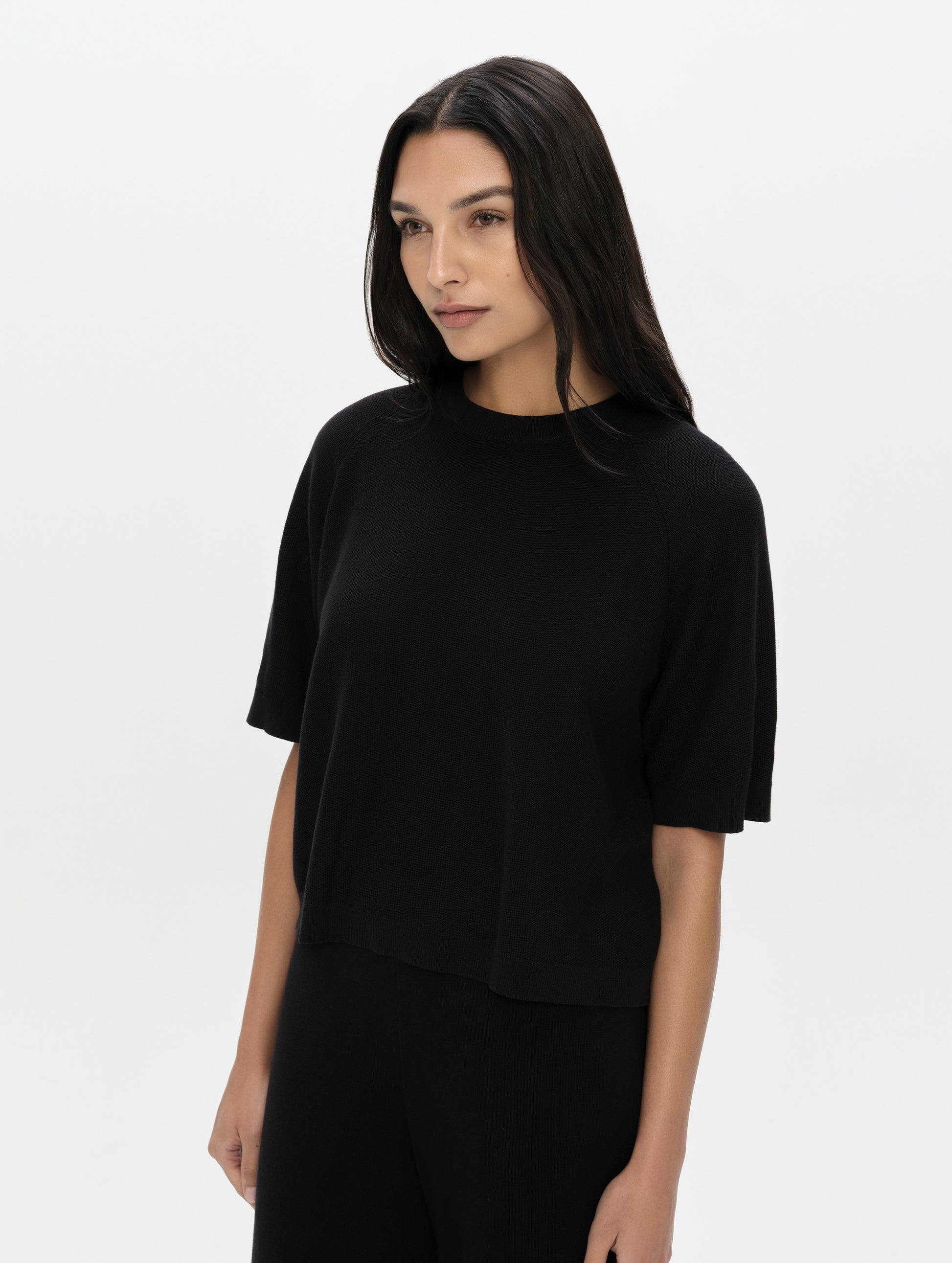 Front, upper-body view of woman wearing the Eliana Sweater Tee in Onyx Black from AETHER Apparel.