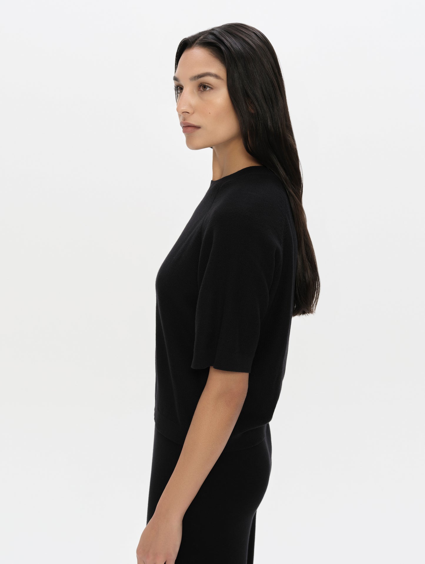 Side profile, upper-body view of woman wearing the Eliana Sweater Tee in Onyx Black from AETHER Apparel.