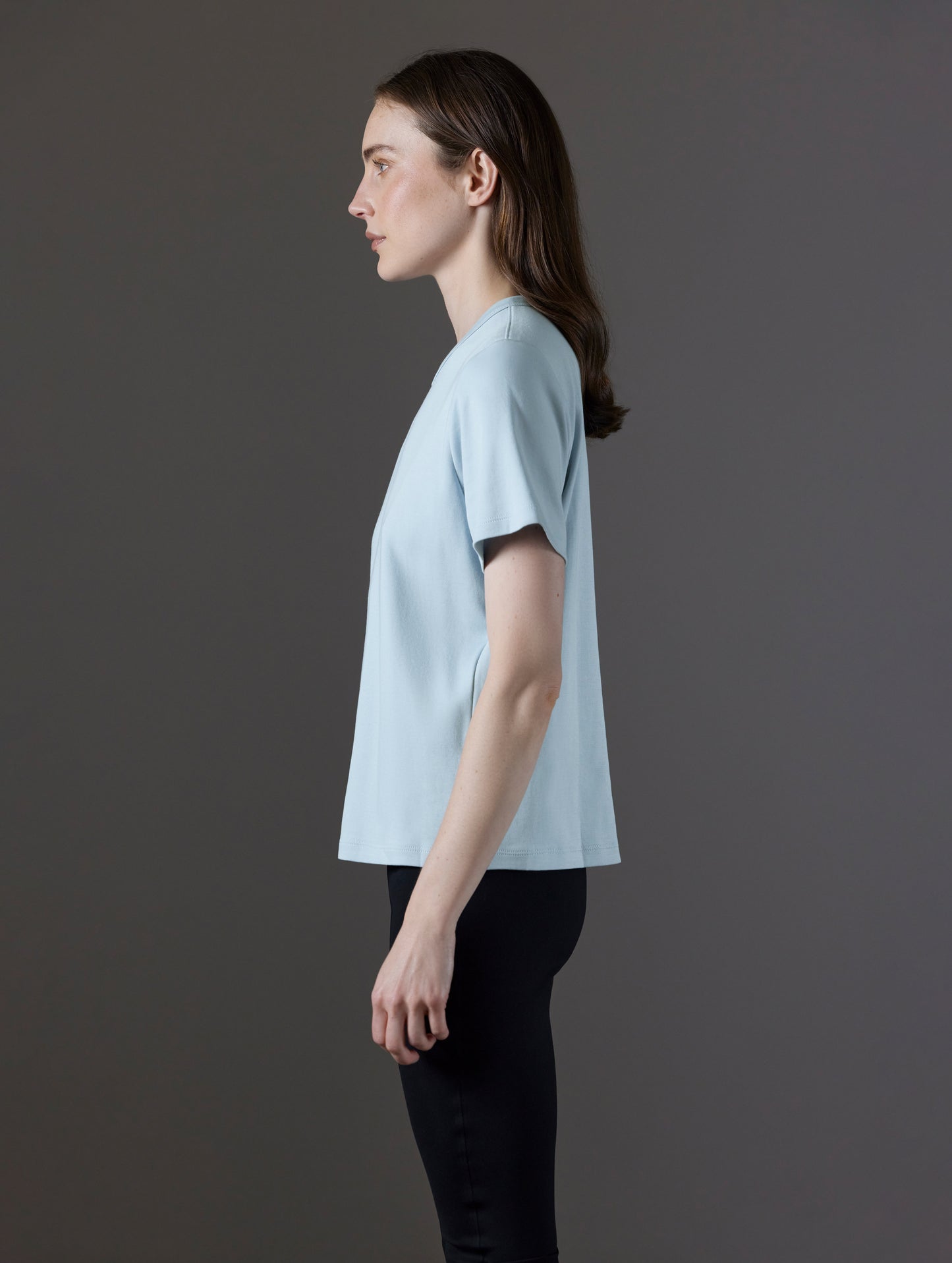 Side profile view of woman wearing Emery Pima Tee in Flight Blue from AETHER Apparel.