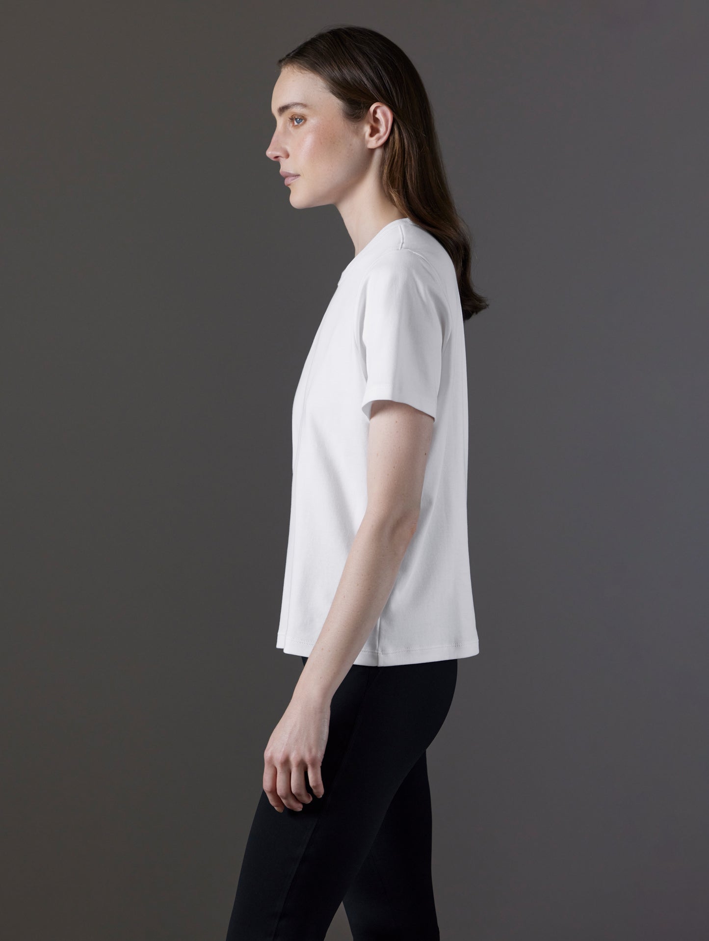 Side profile view of woman wearing Emery Pima Tee in White from AETHER Apparel.