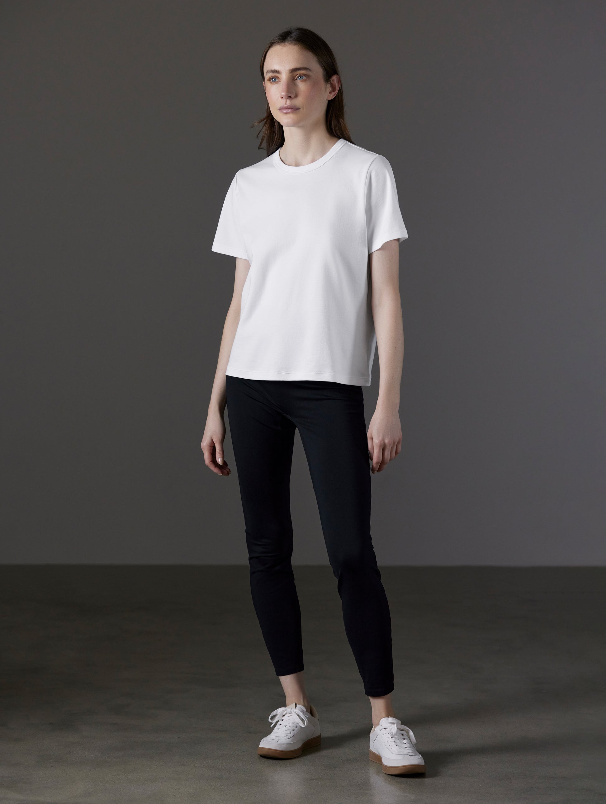 Front angled full-body view of woman wearing Emery Pima Tee in White from AETHER Apparel.