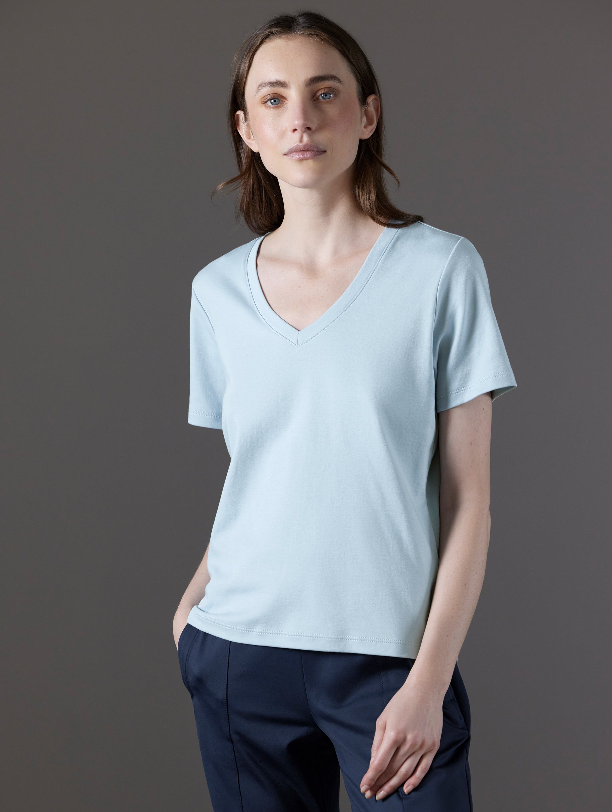 Front angled view of woman wearing Emery Pima V-Neck Tee in Flight Blue from AETHER Apparel.