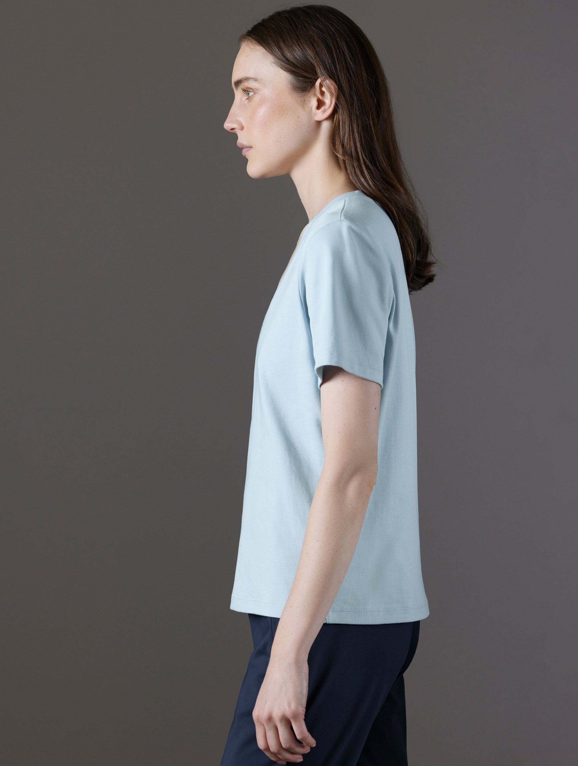 Side profile view of woman wearing Emery Pima V-Neck Tee in Flight Blue from AETHER Apparel.