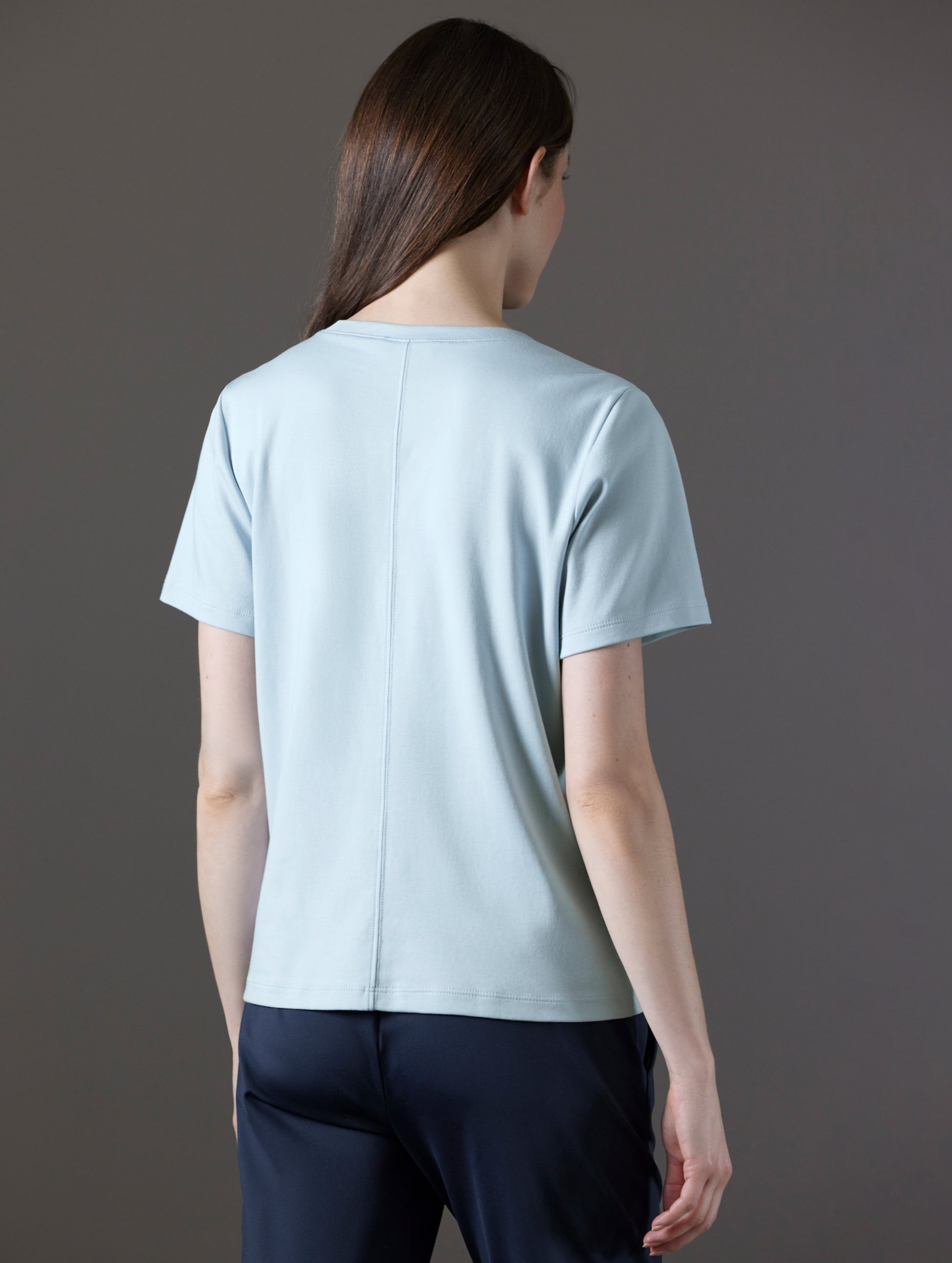 Rear angled view of woman wearing Emery Pima V-Neck Tee in Flight Blue from AETHER Apparel.