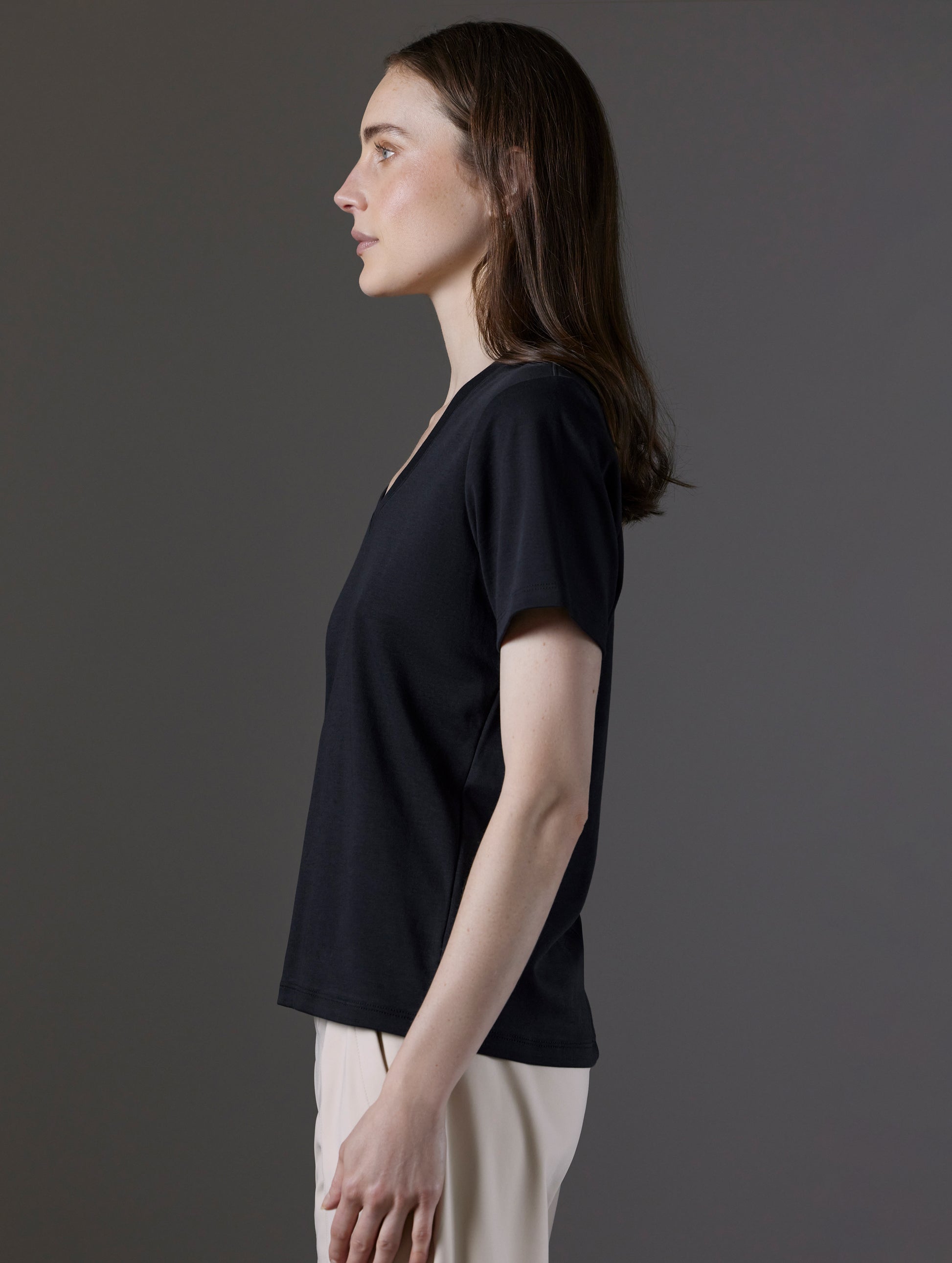 Side profile view of woman wearing Emery Pima V-Neck Tee in Onyx Black from AETHER Apparel.