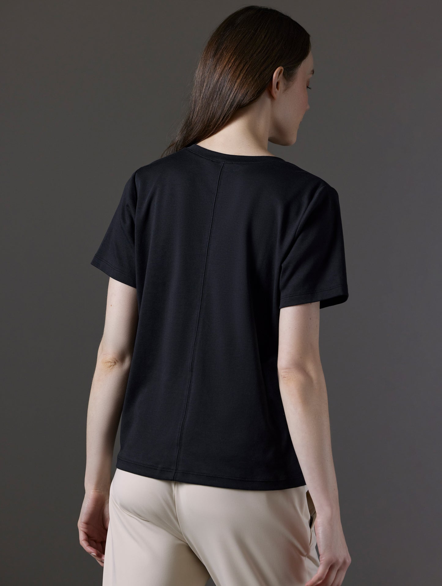 Rear angled view of woman wearing Emery Pima V-Neck Tee in Onyx Black from AETHER Apparel.