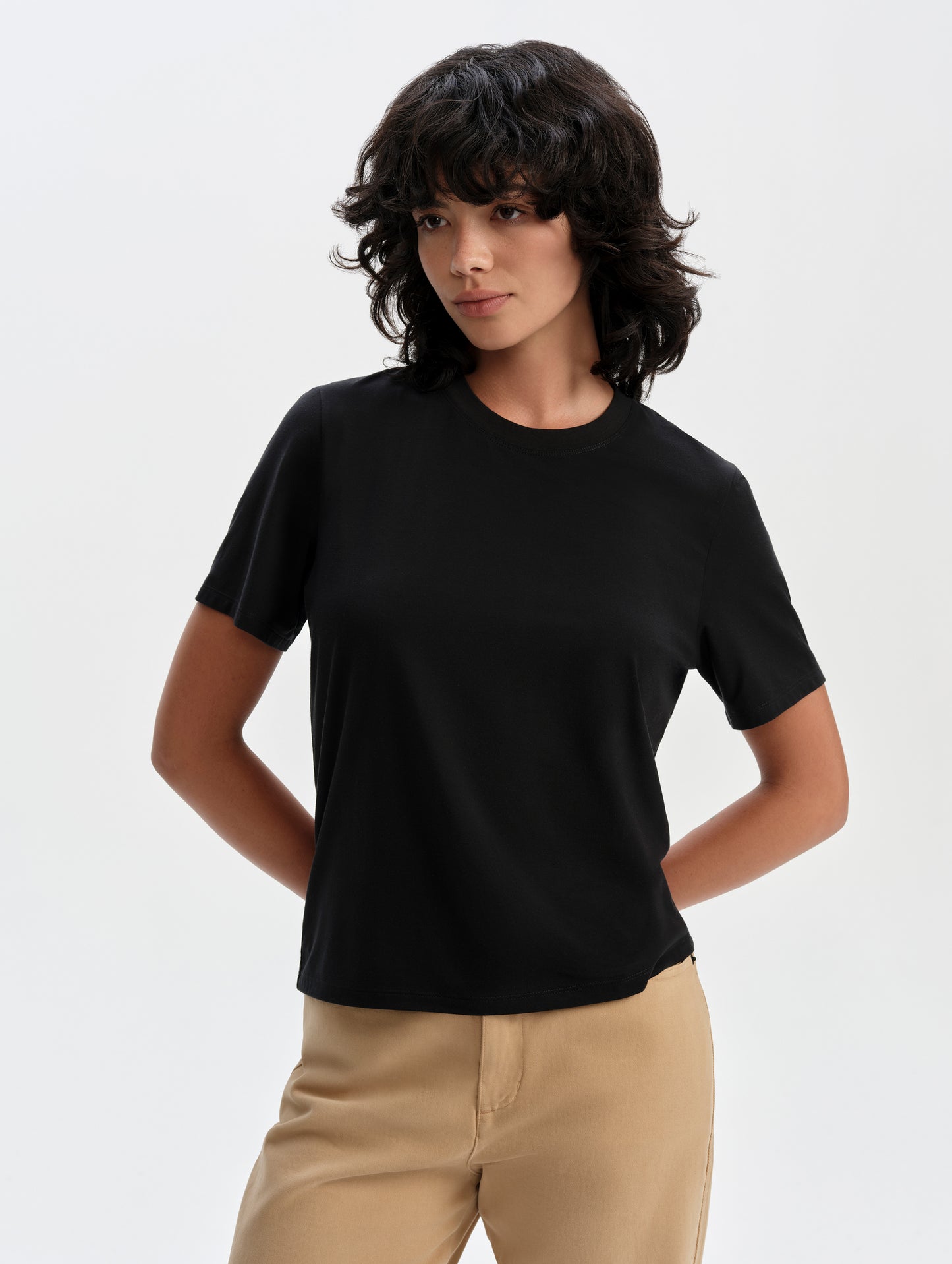 Front upper-body view of woman wearing the Hana Short-Sleeve Tee Shirt in Onyx Black from AETHER Apparel.