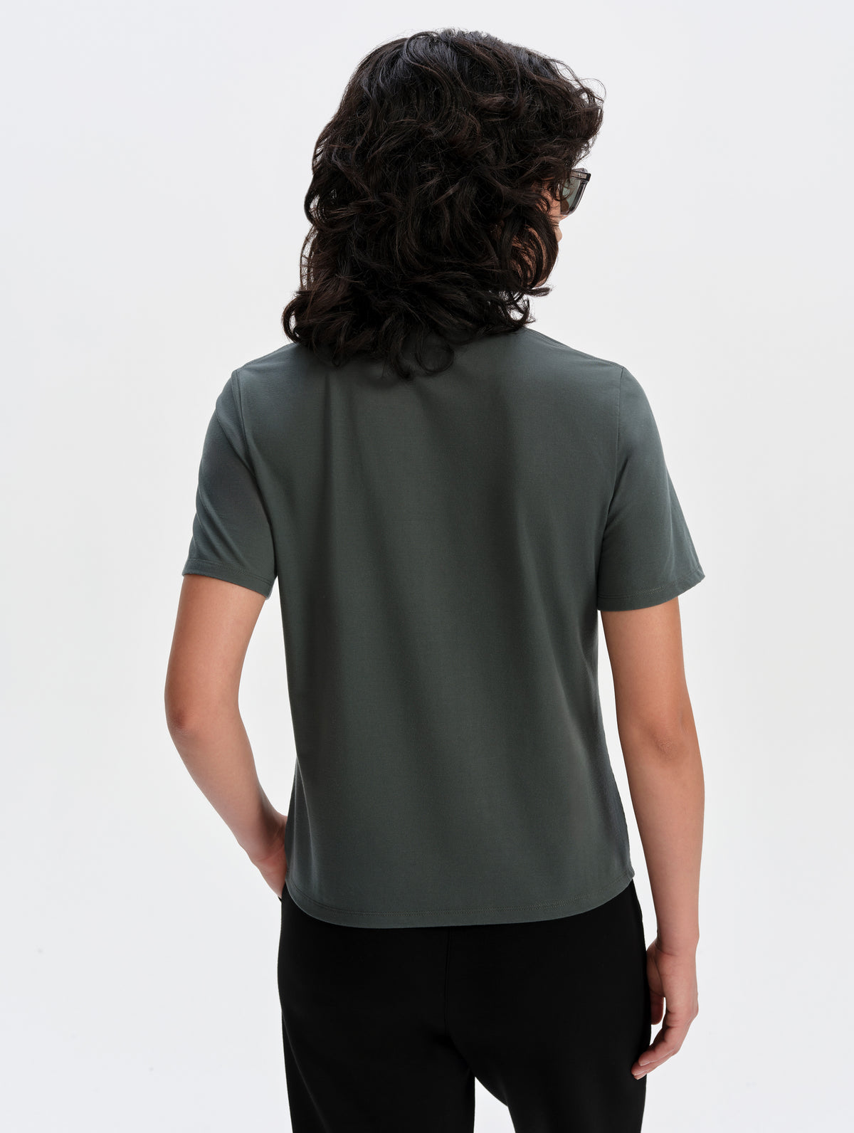 Rear upper-body view of woman wearing the Hana Short-Sleeve Tee Shirt in Saville Green from AETHER Apparel.