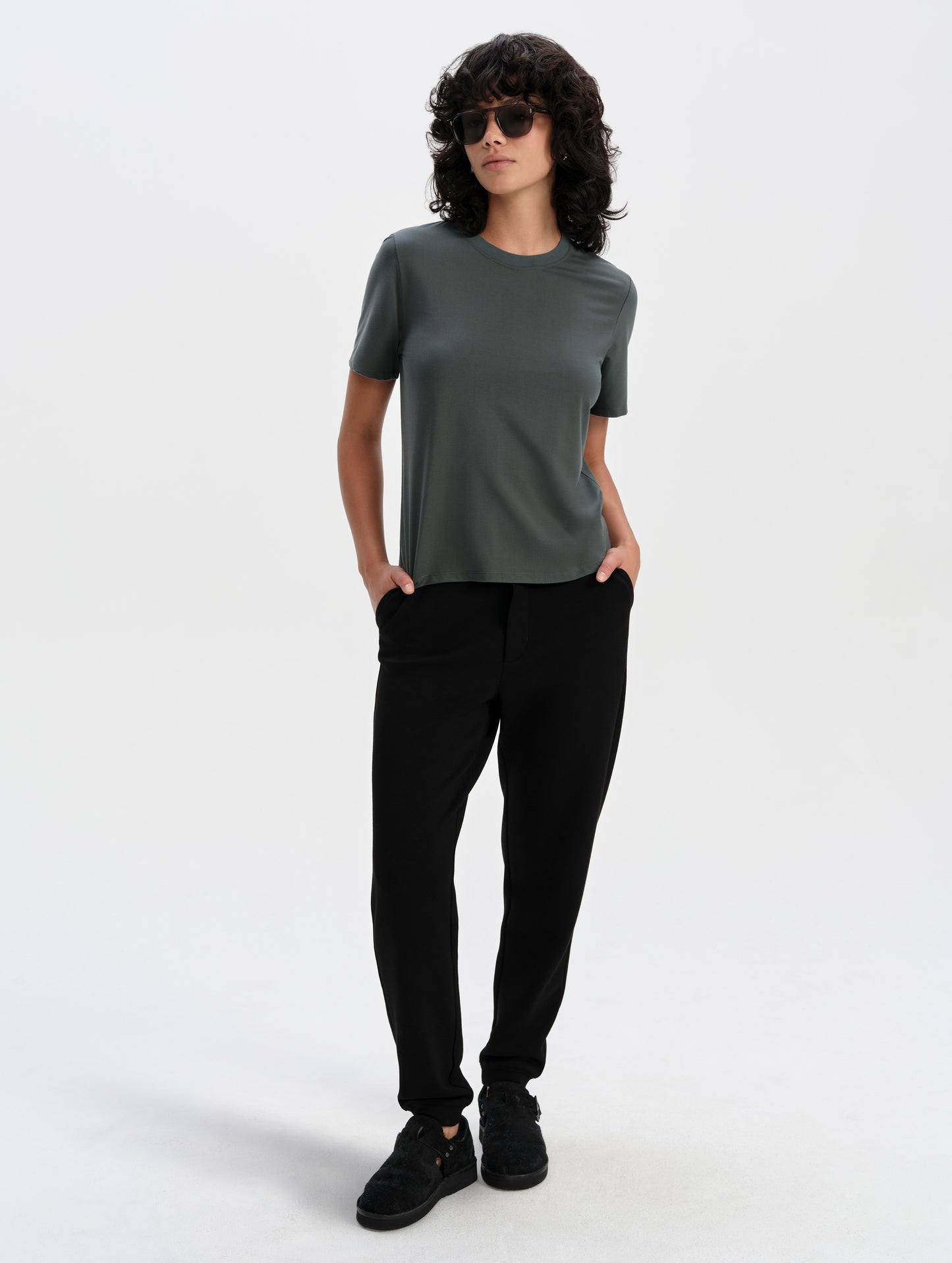 Front full-body view of woman wearing the Hana Short-Sleeve Tee Shirt in Saville Green from AETHER Apparel.