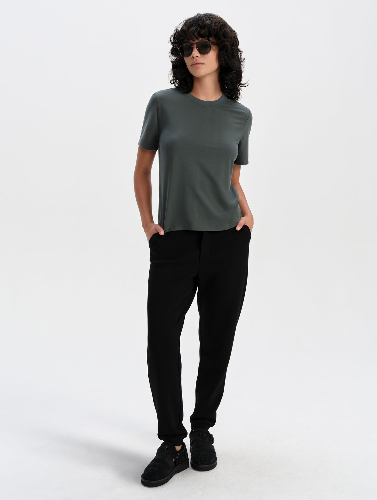 Front full-body view of woman wearing the Hana Short-Sleeve Tee Shirt in Saville Green from AETHER Apparel.