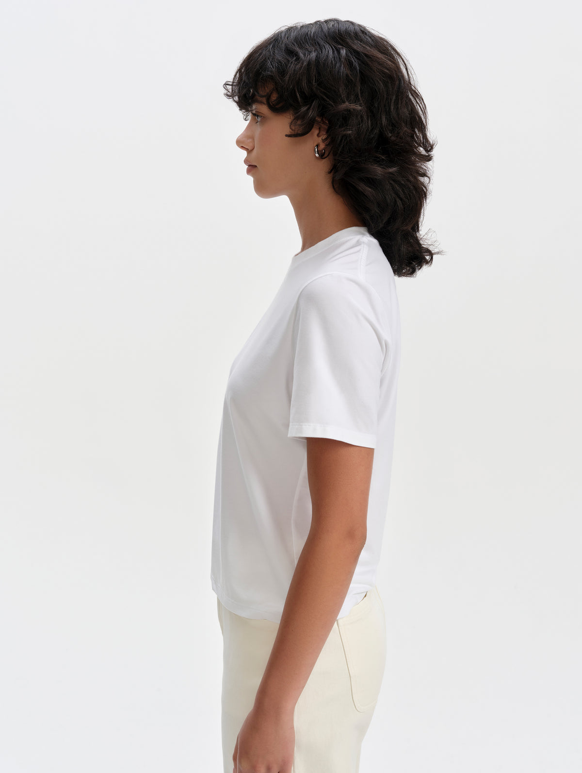Side profile upper-body view of woman wearing the Hana Short-Sleeve Tee Shirt in White from AETHER Apparel.
