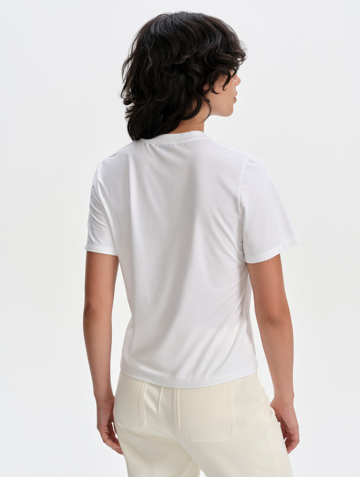 Rear upper-body view of woman wearing the Hana Short-Sleeve Tee Shirt in White from AETHER Apparel.