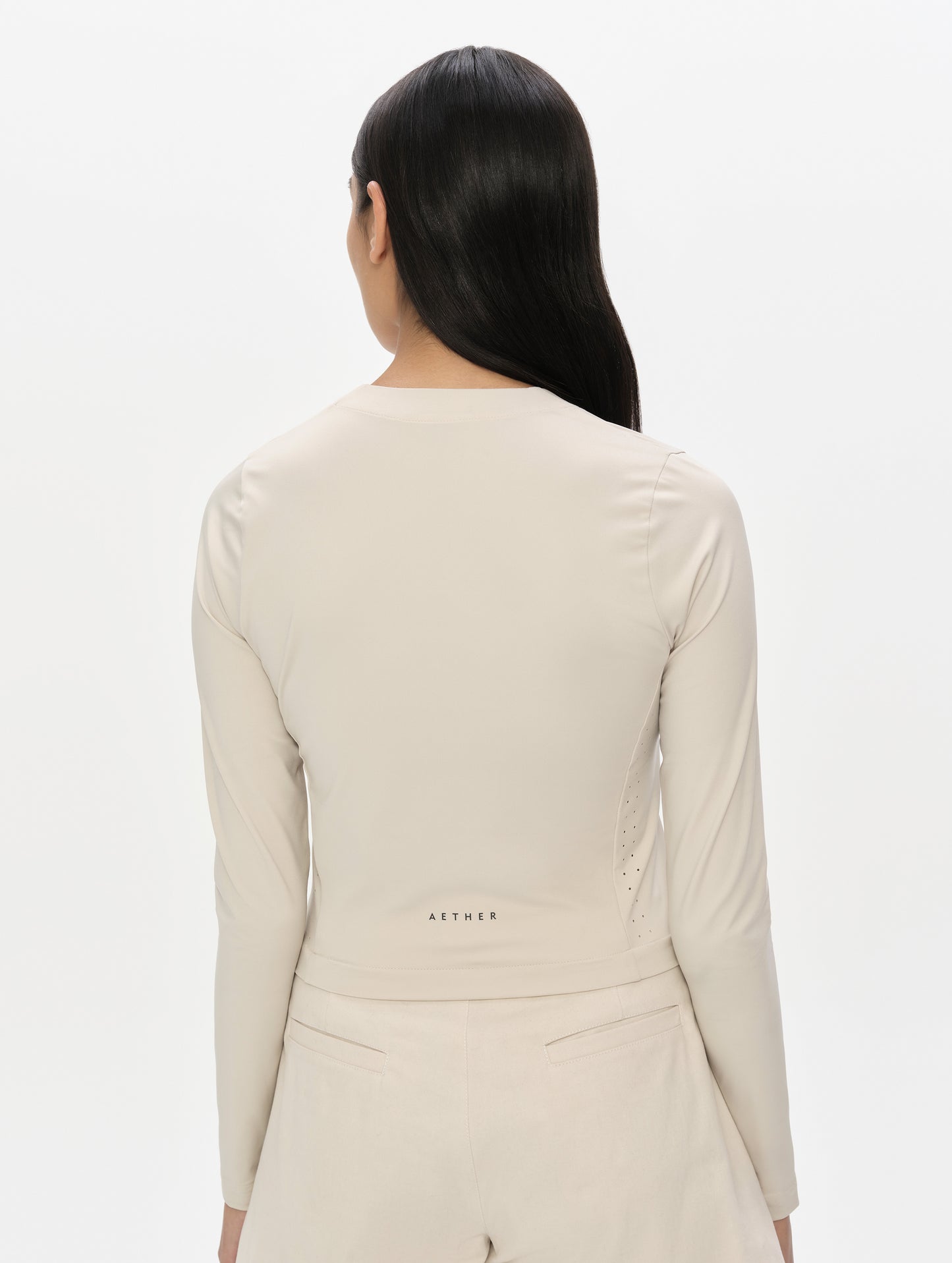 Rear, upper-body view of woman wearing the Kora Sunproof Shirt in Bone from AETHER Apparel.