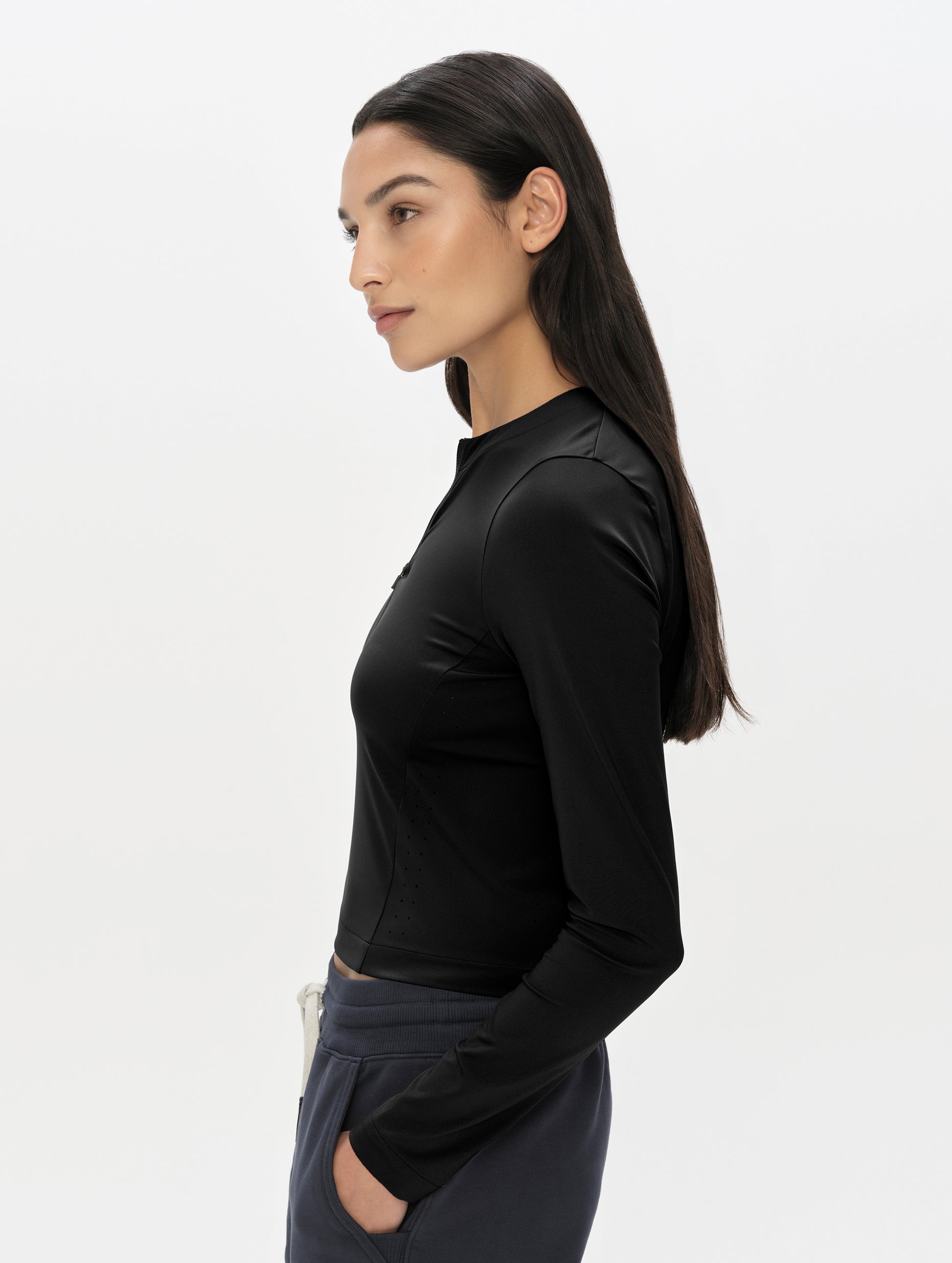 Side profile, upper-body view of woman wearing the Kora Sunproof Shirt in Onyx Black from AETHER Apparel.