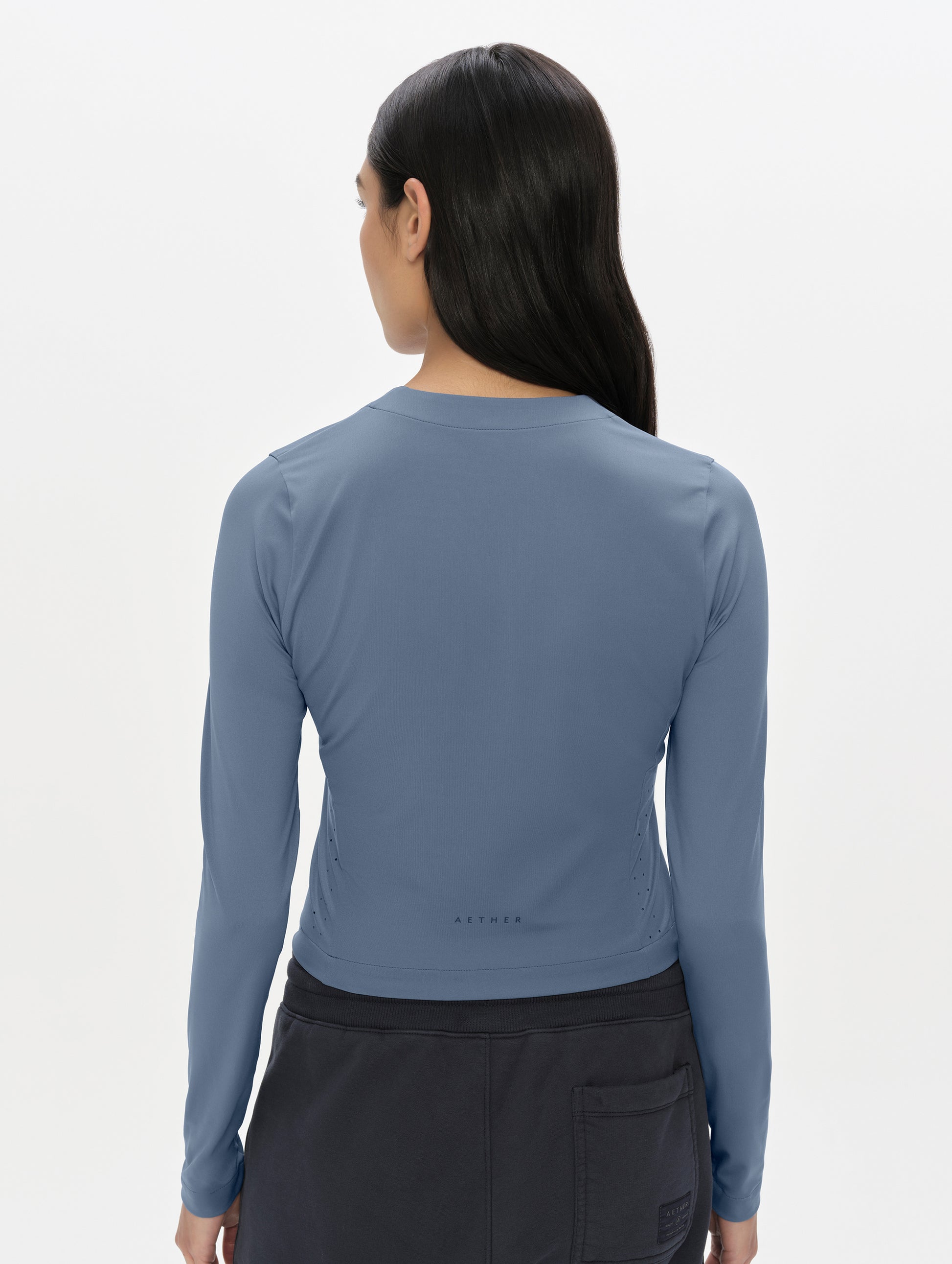 Rear, upper-body view of woman wearing the Kora Sunproof Shirt in Portal Blue from AETHER Apparel.