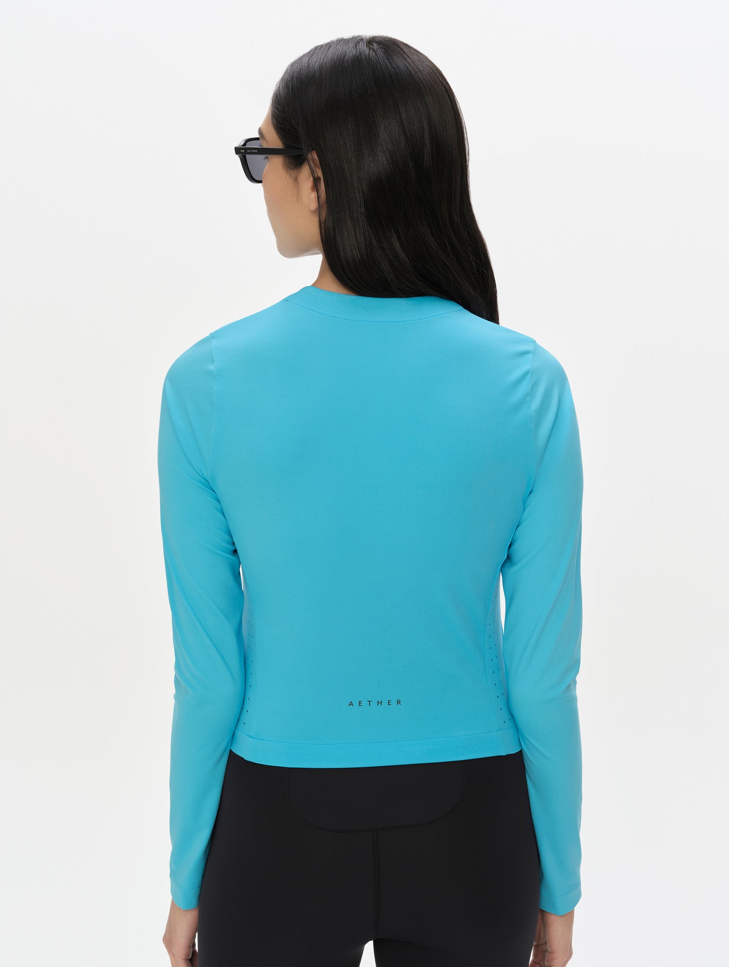 Rear, upper-body view of woman wearing the Kora Sunproof Shirt in Sky Blue from AETHER Apparel.