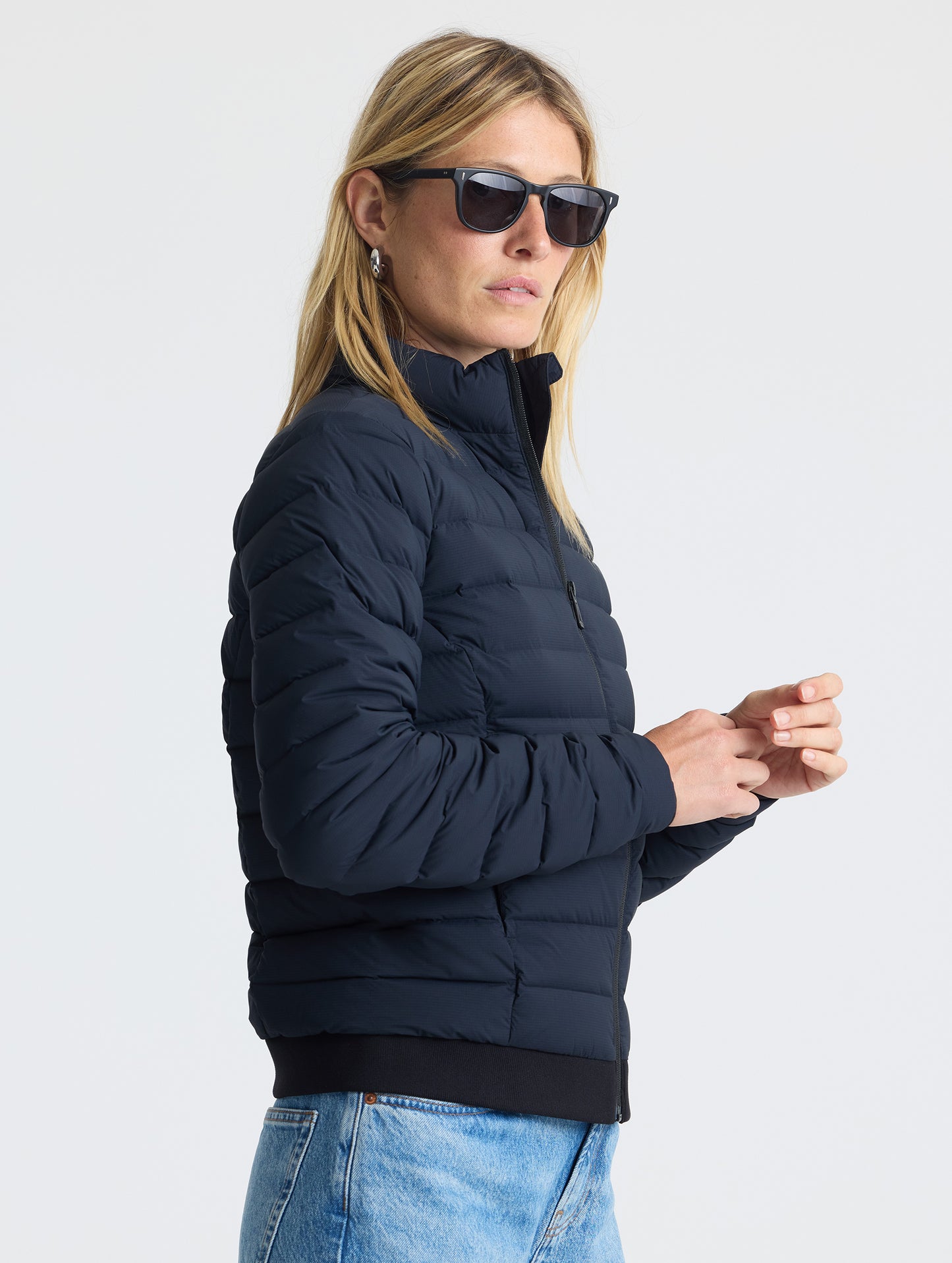 Angled right view of woman wearing W Launch Full-Zip Jacket NH in Onyx Black from AETHER Apparel.