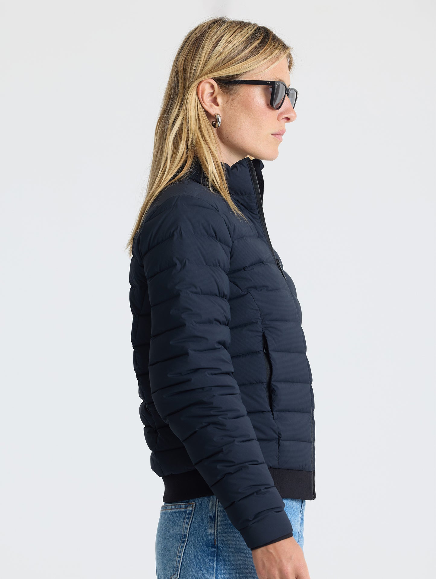 Right profile view of woman wearing W Launch Full-Zip Jacket NH in Onyx Black from AETHER Apparel.