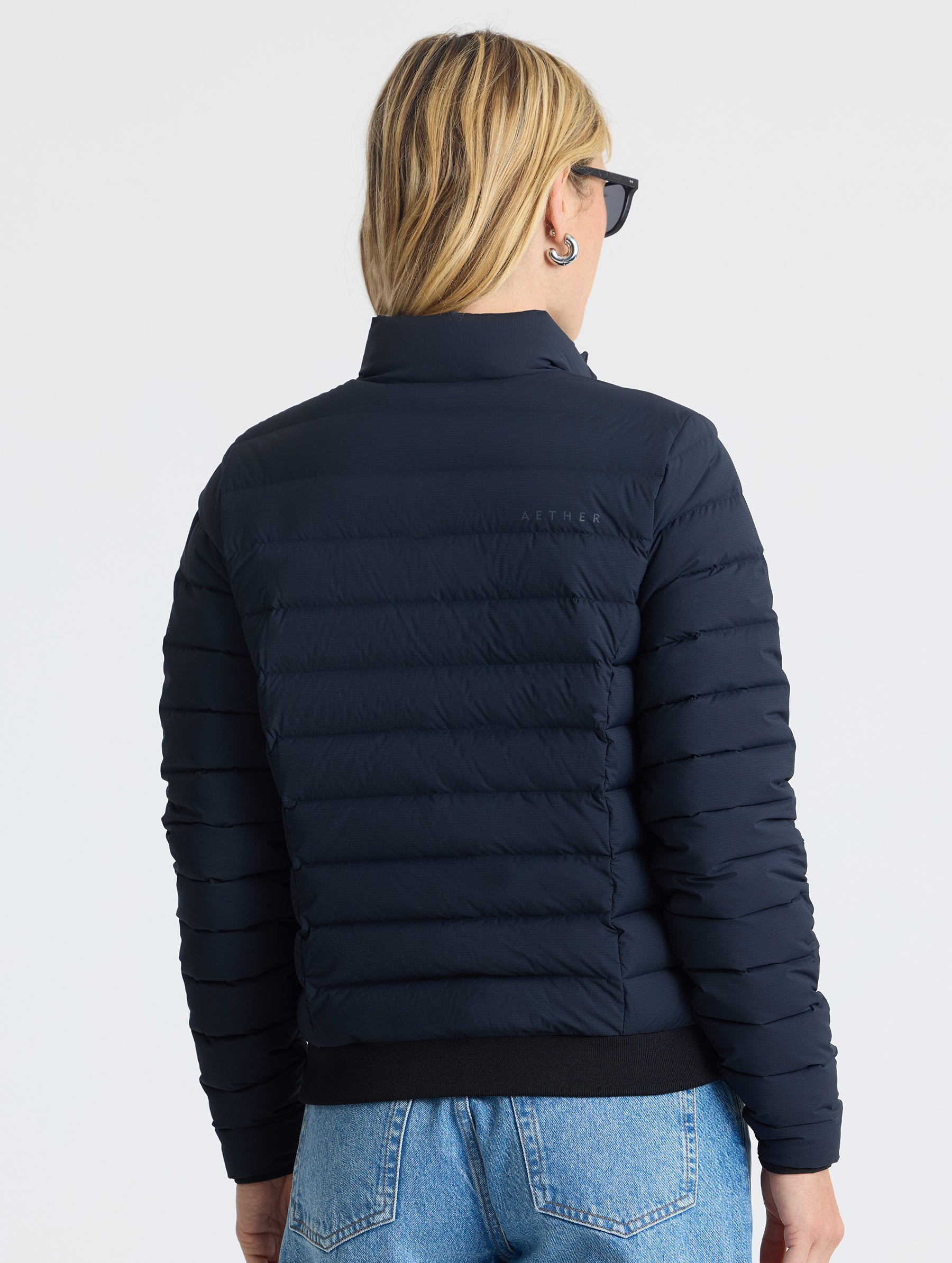 Rear view of woman wearing W Launch Full-Zip Jacket NH in Onyx Black from AETHER Apparel.