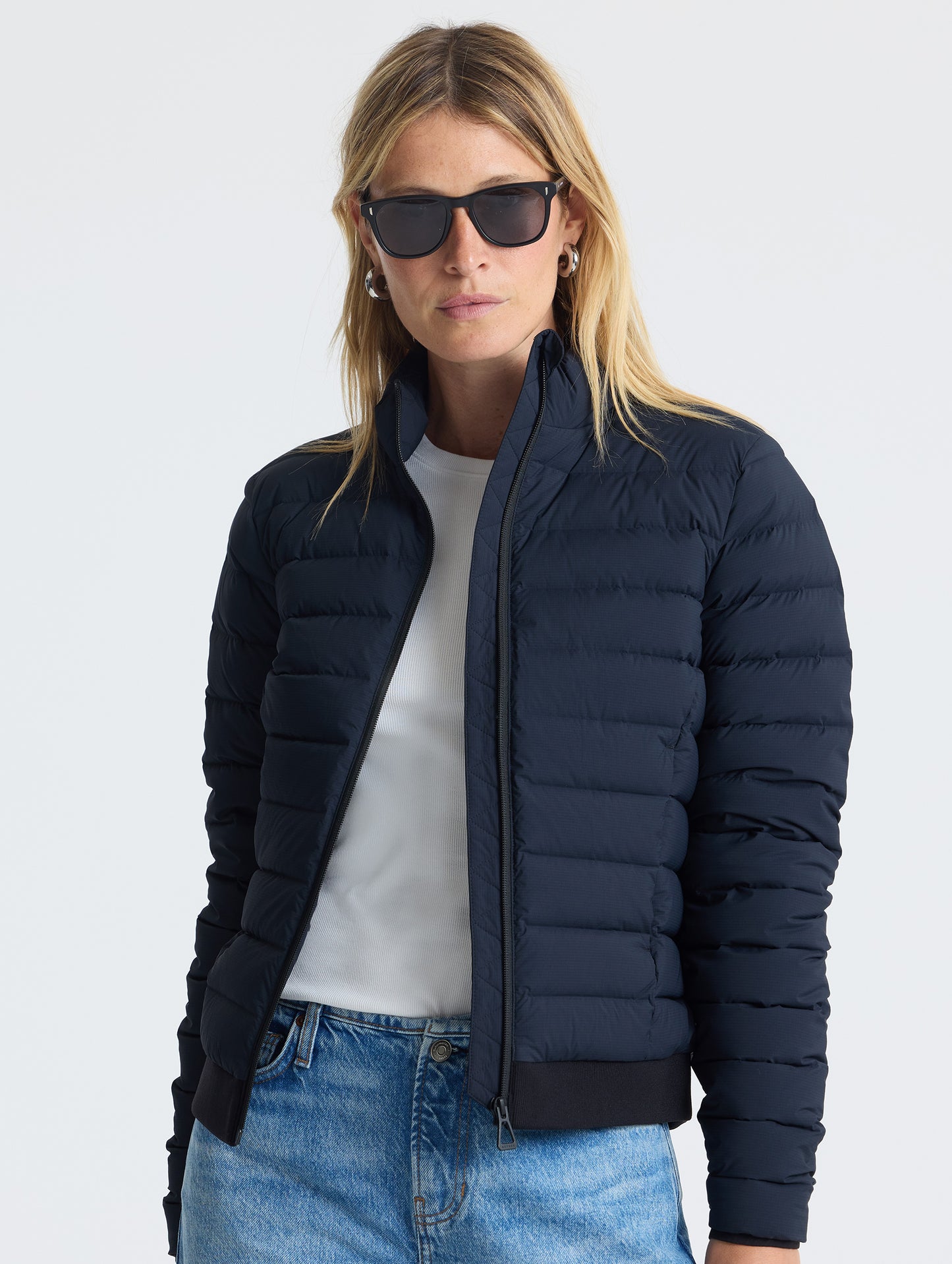 Front view of woman wearing unzipped W Launch Full-Zip Jacket NH in Onyx Black from AETHER Apparel.