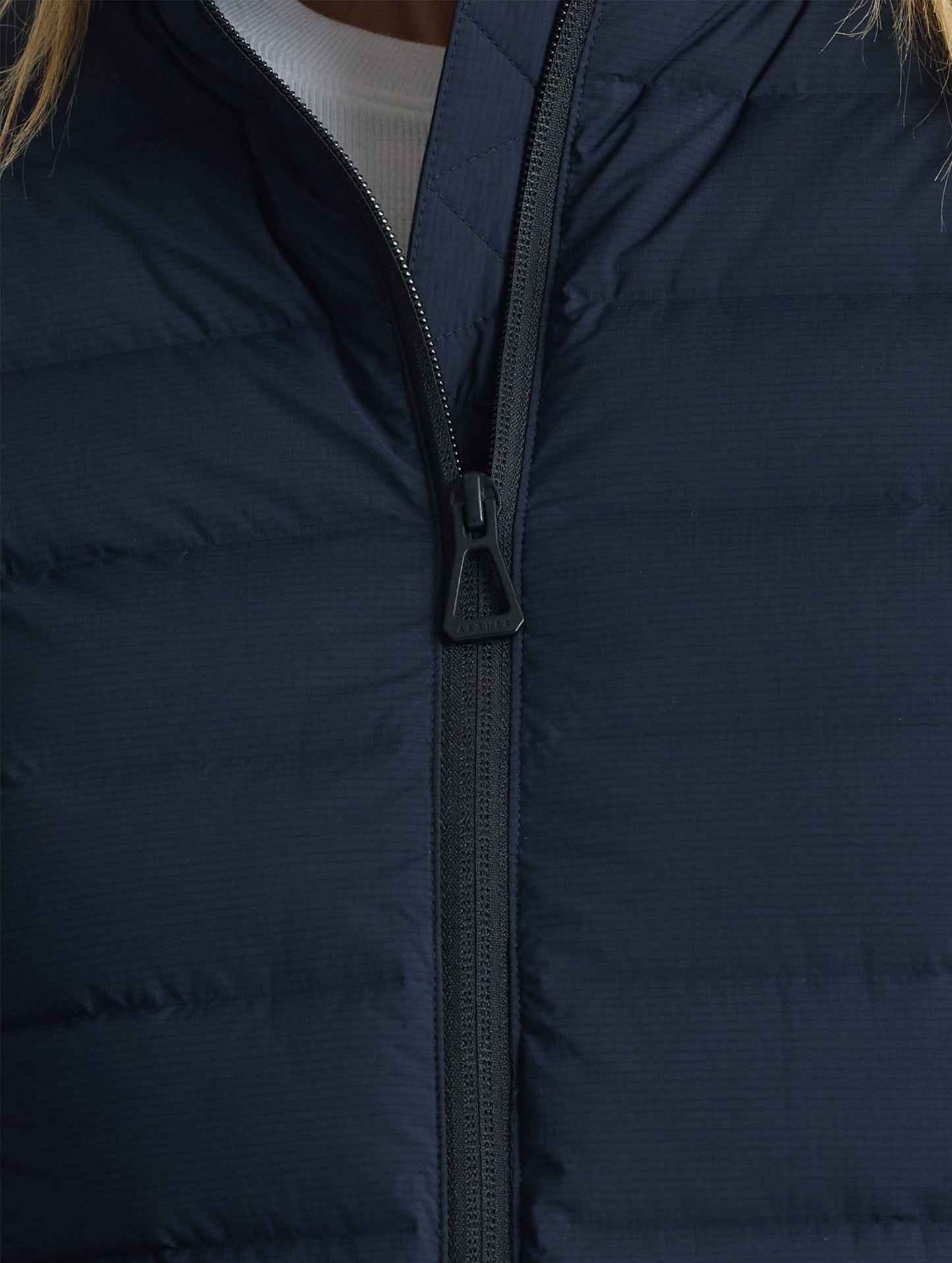 Closeup view of front center zipper of W Launch Full-Zip Jacket NH in Onyx Black from AETHER Apparel.