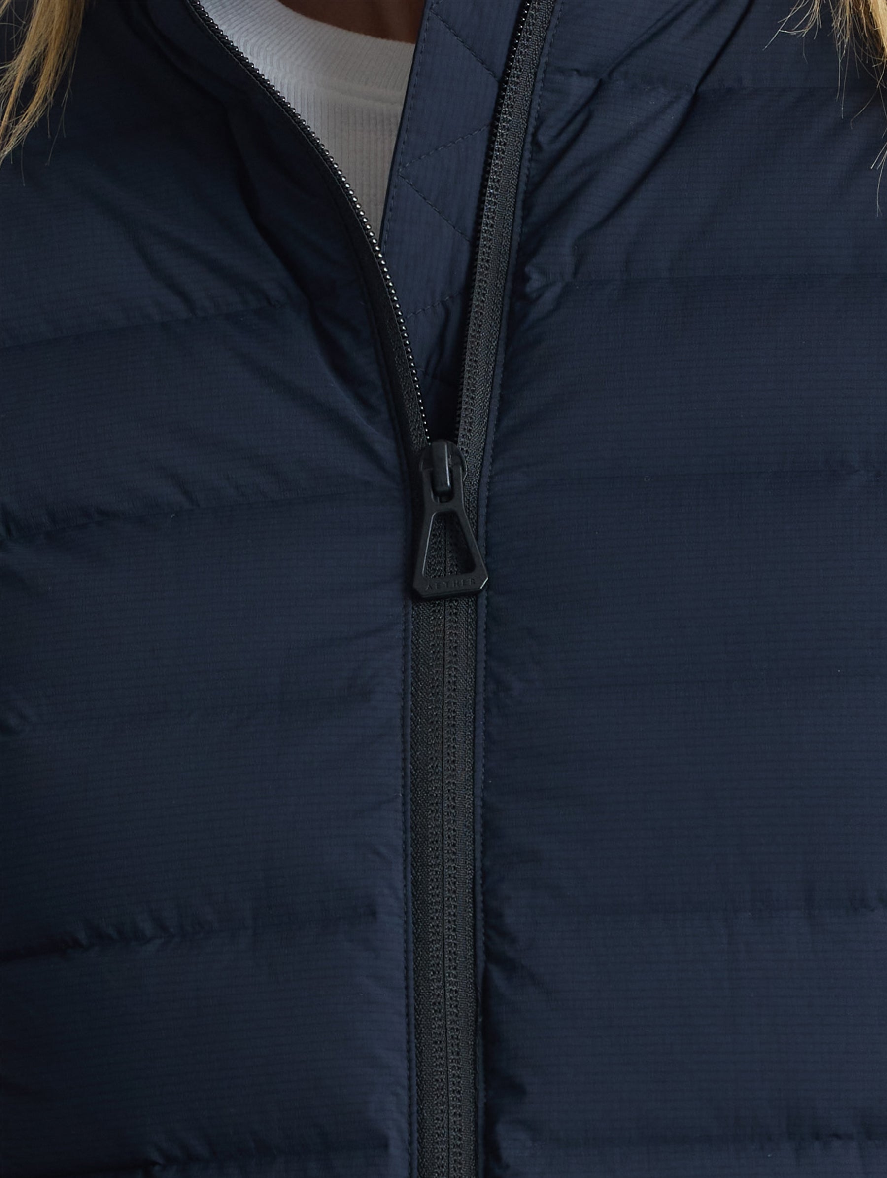 Closeup view of front center zipper of W Launch Full-Zip Jacket NH in Onyx Black from AETHER Apparel.