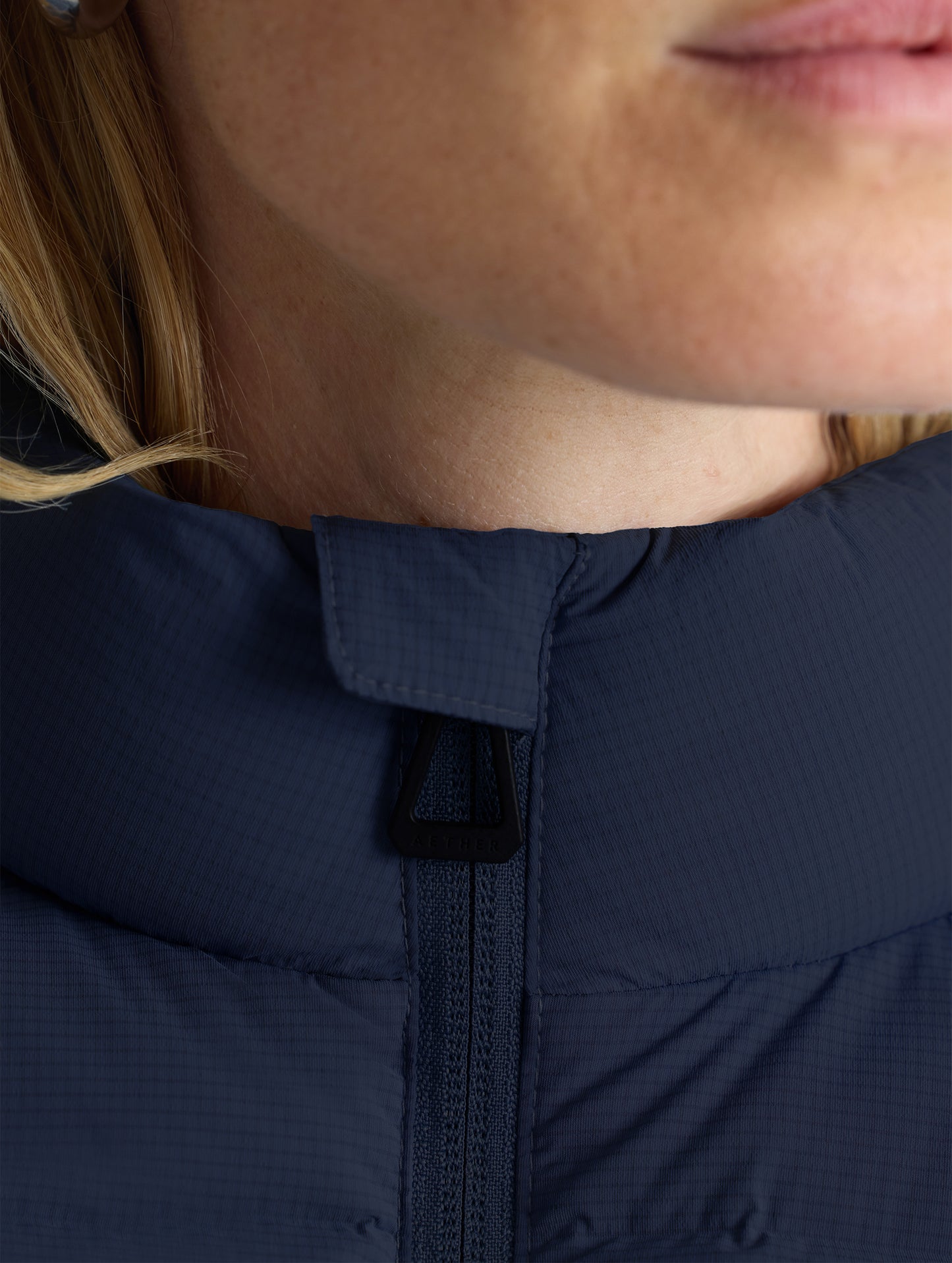 Closeup detail view of woman's collar of W Launch Full-Zip Jacket NH in Onyx Black from AETHER Apparel.