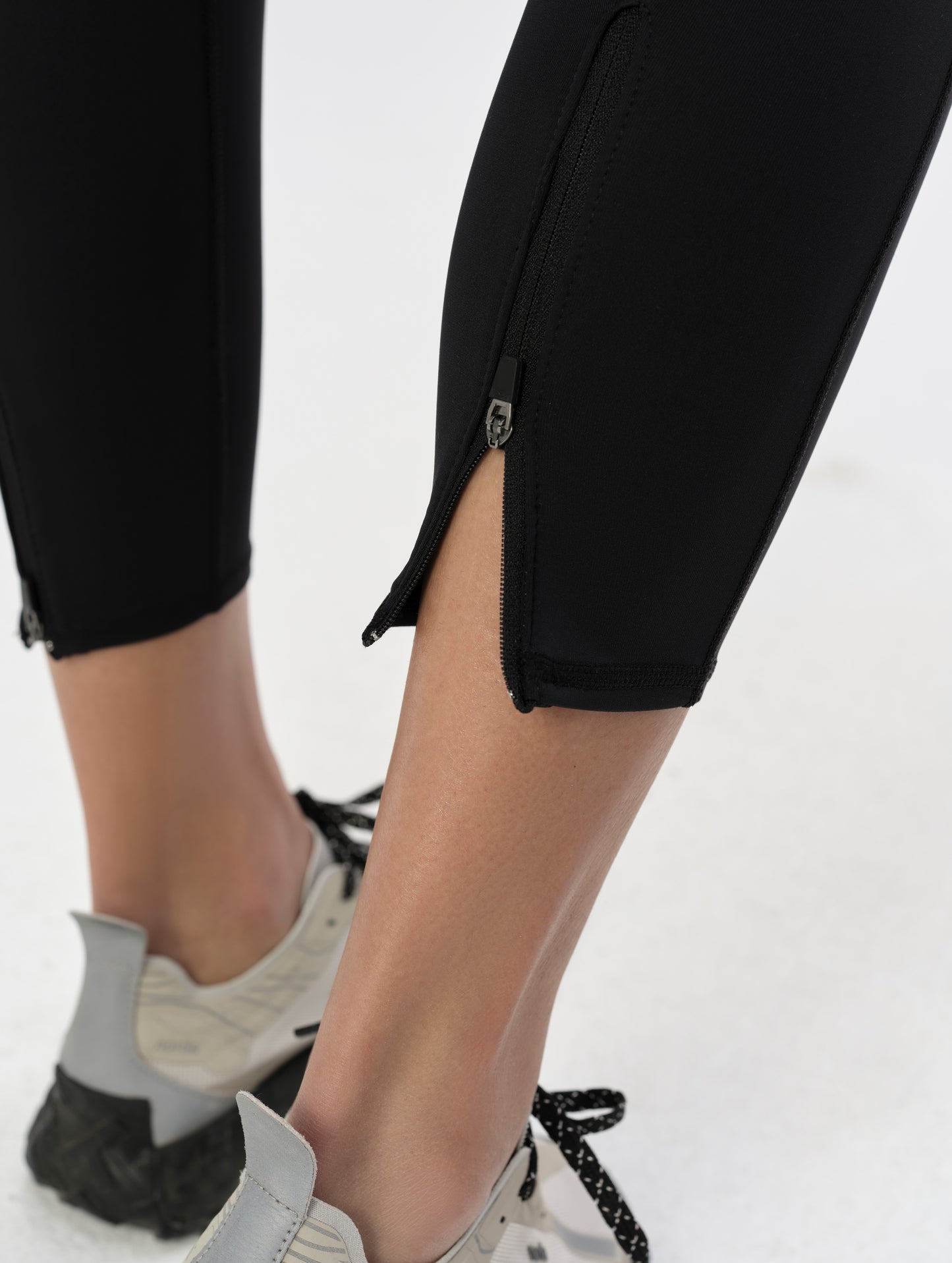 Closeup detailed view of the zippered cuff openings on the Laurel Legging in Onyx Black from AETHER.