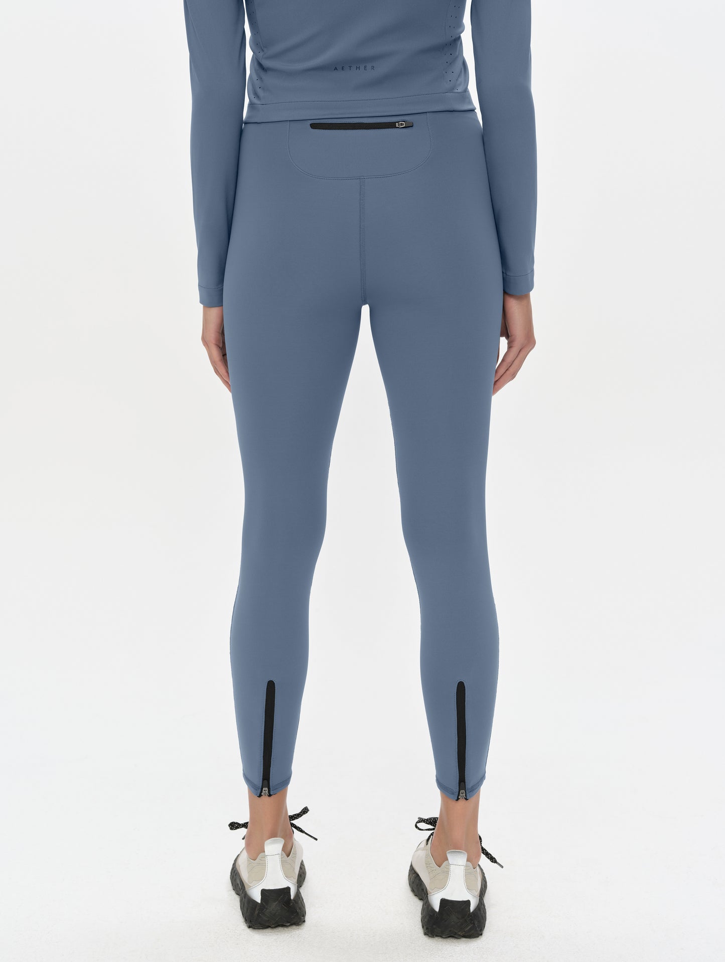 Rear, lower-body view of woman wearing the Laurel Legging in Portal Blue from AETHER Apparel.