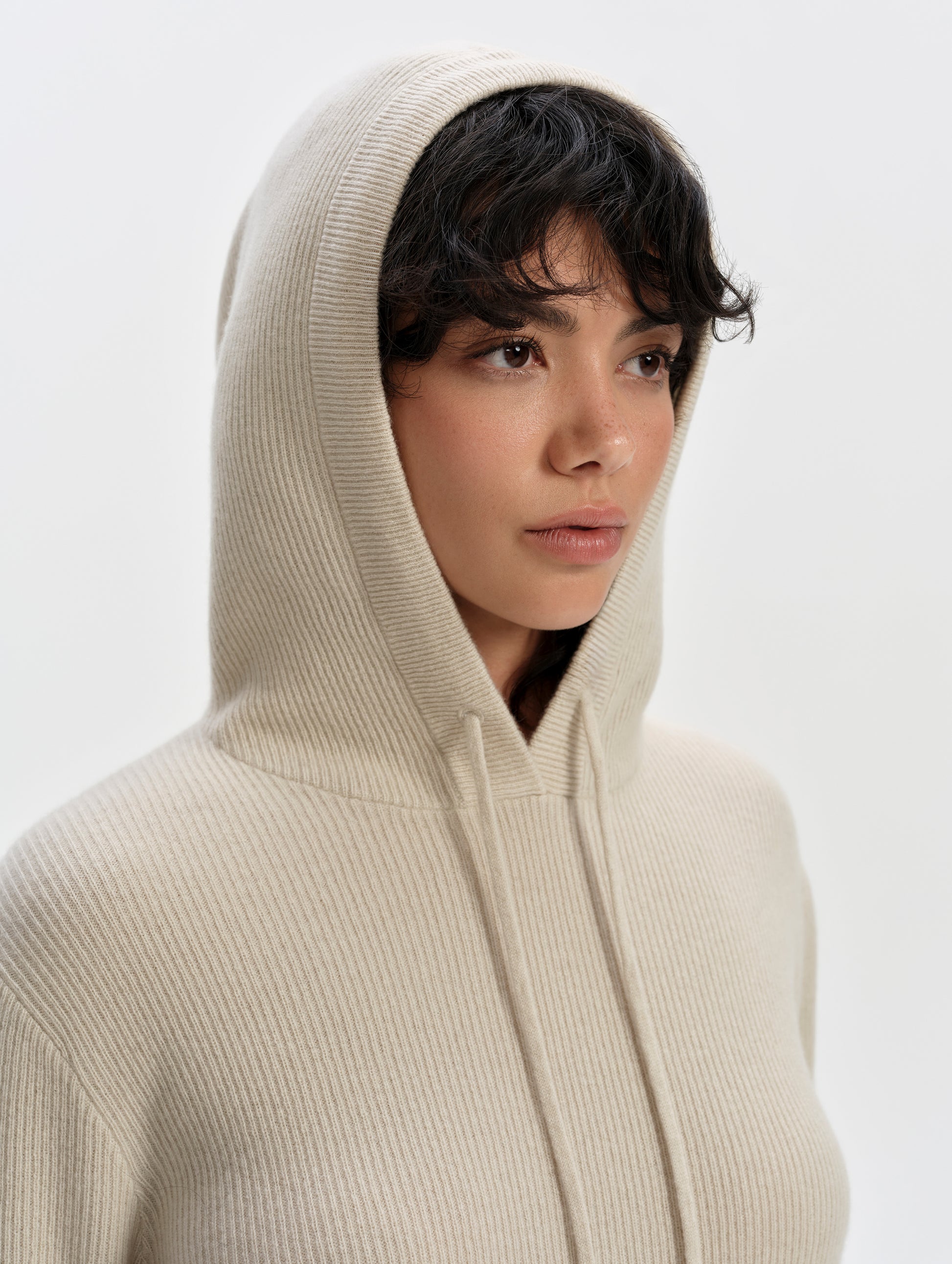 Closeup view of woman wearing the Lawrence Cashmere Hooded Sweater in Bone from AETHER Apparel with hood up. 