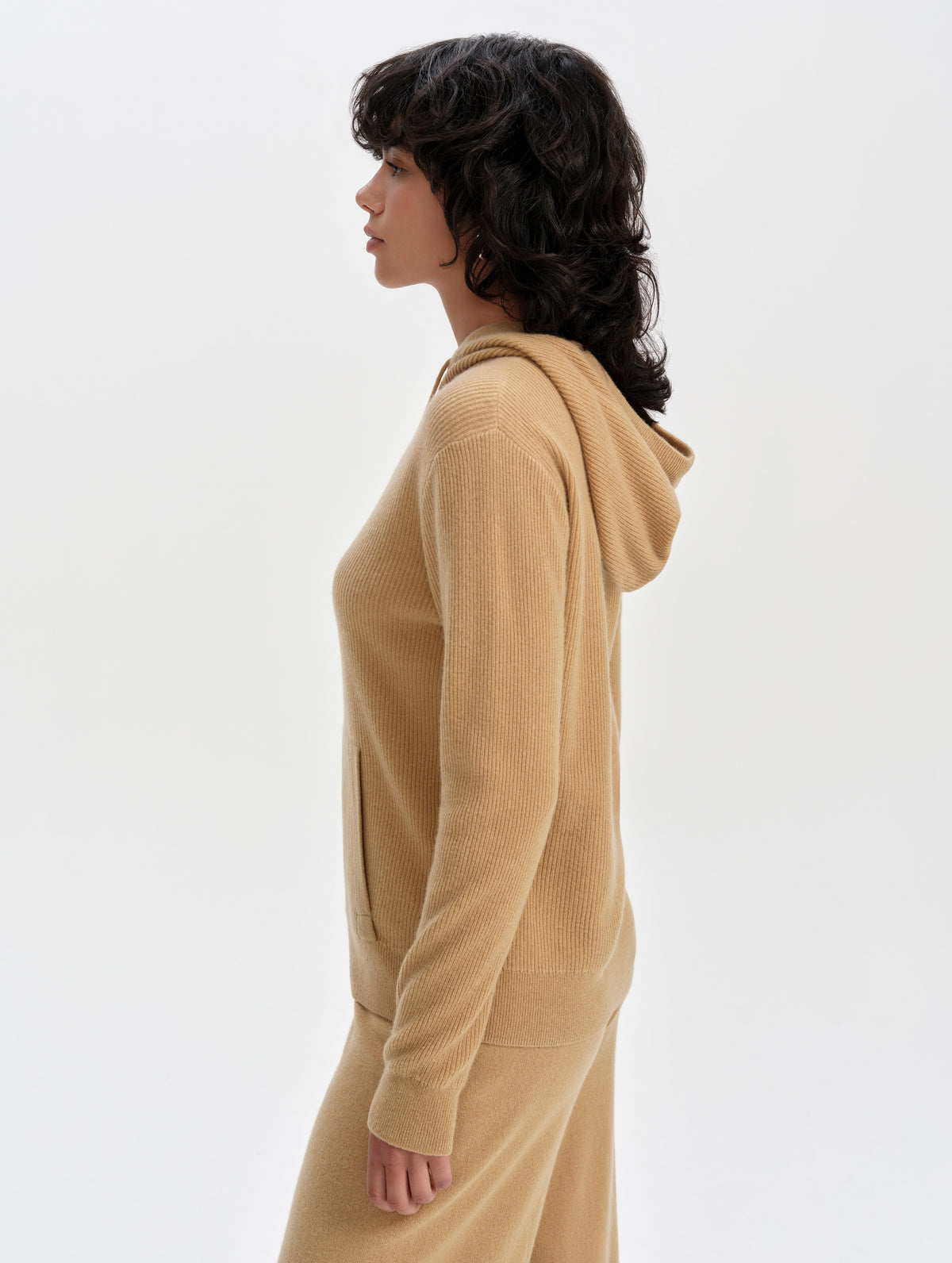 Side profile upper-body view of woman wearing the Lawrence Cashmere Hooded Sweater in Latte Brown from AETHER Apparel.