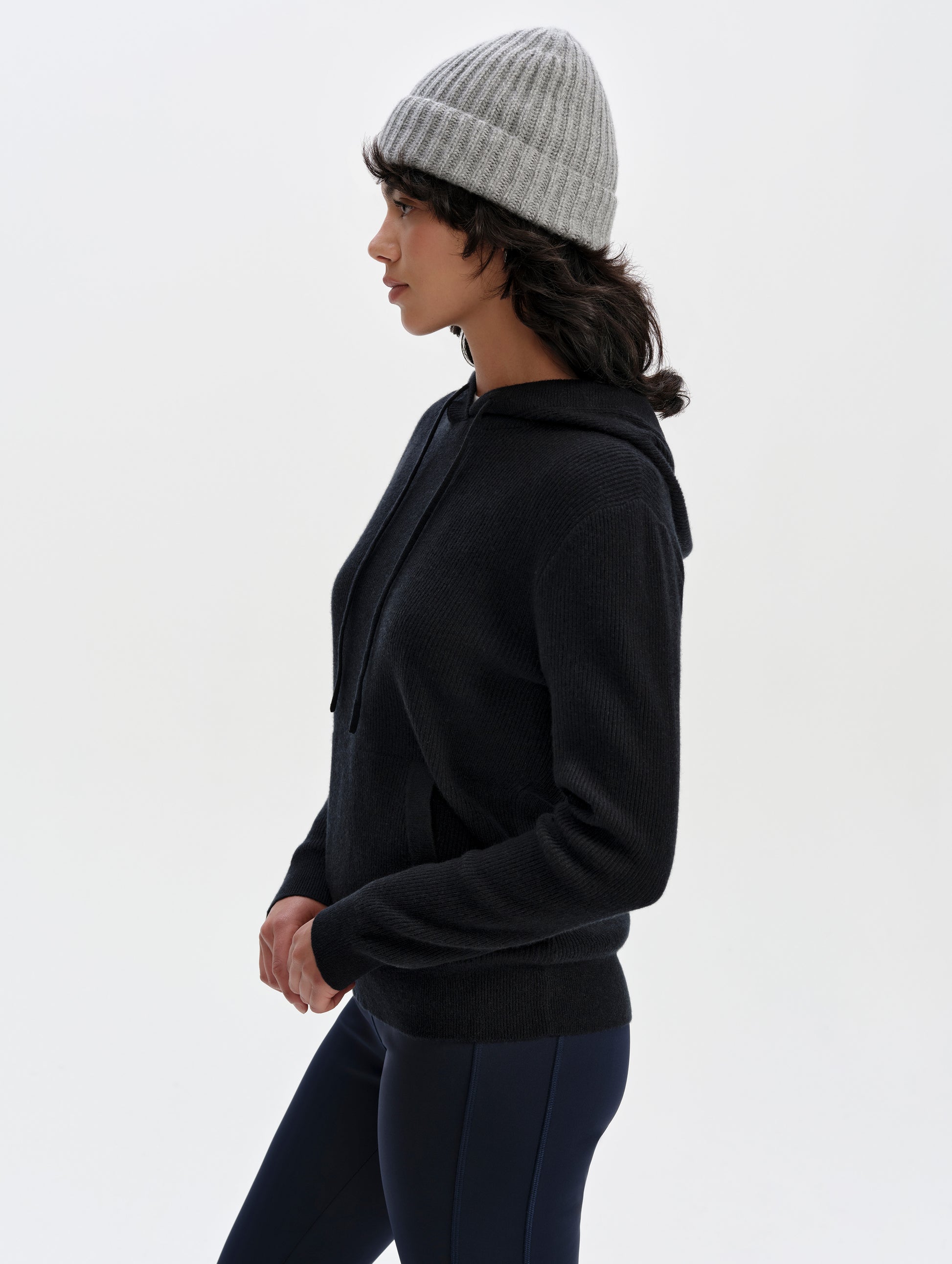 Side profile upper-body view of woman wearing the Lawrence Cashmere Hooded Sweater in Onyx Black from AETHER Apparel.