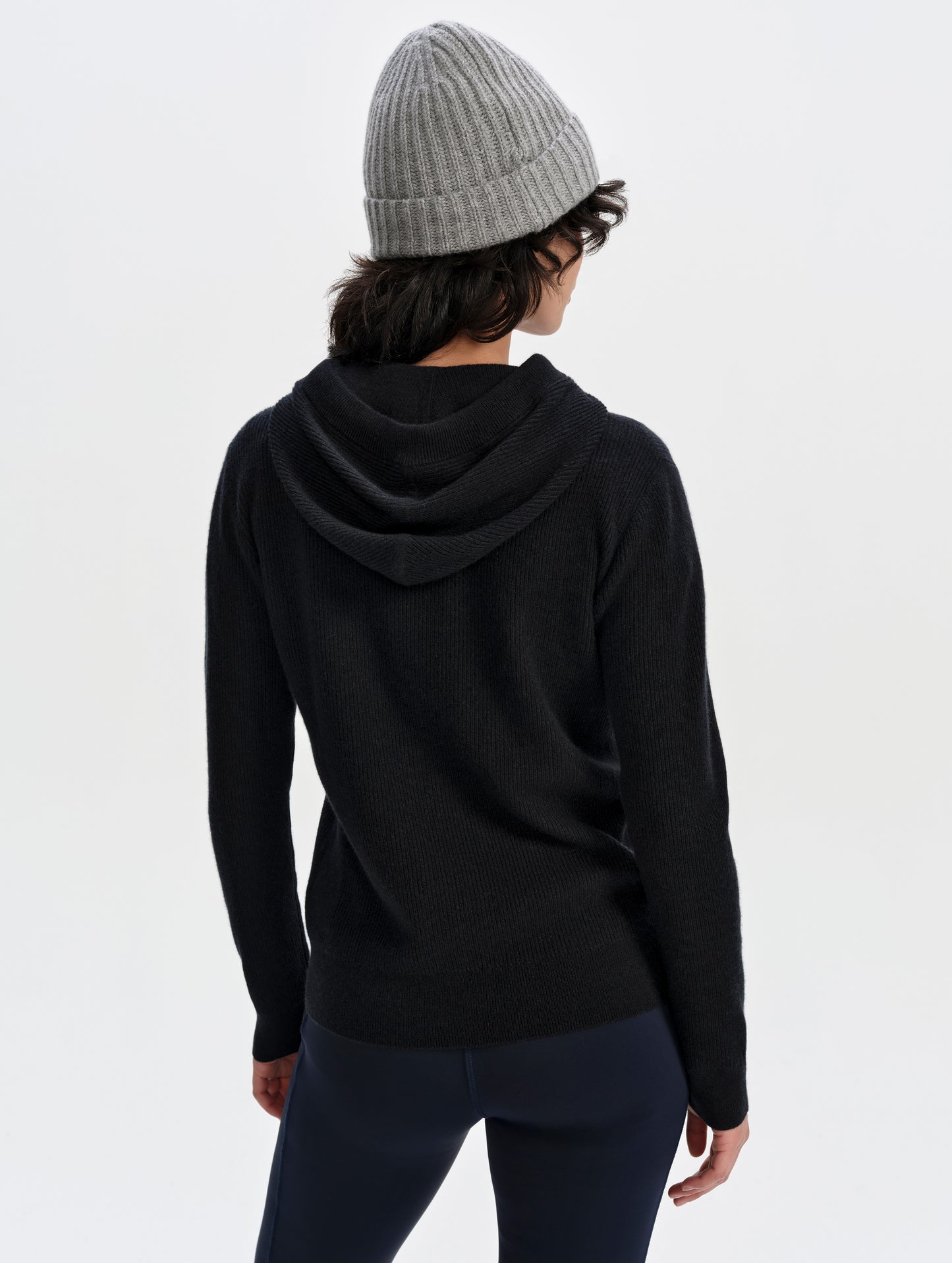 Rear upper-body view of woman wearing the Lawrence Cashmere Hooded Sweater in Onyx Black from AETHER Apparel.
