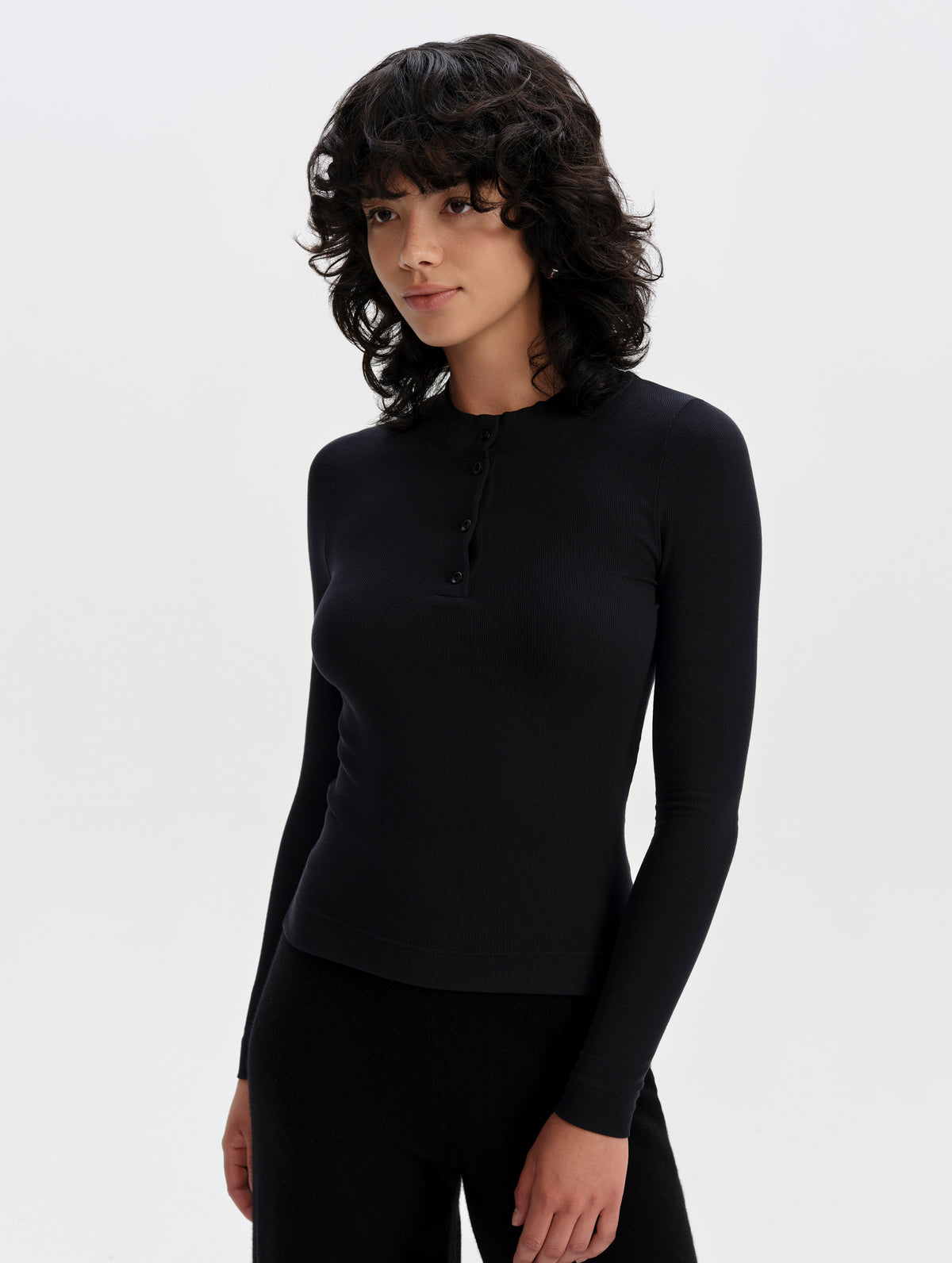 Front upper-body view of woman wearing the Legacy Long-Sleeve Henley in Onyx Black from AETHER Apparel.