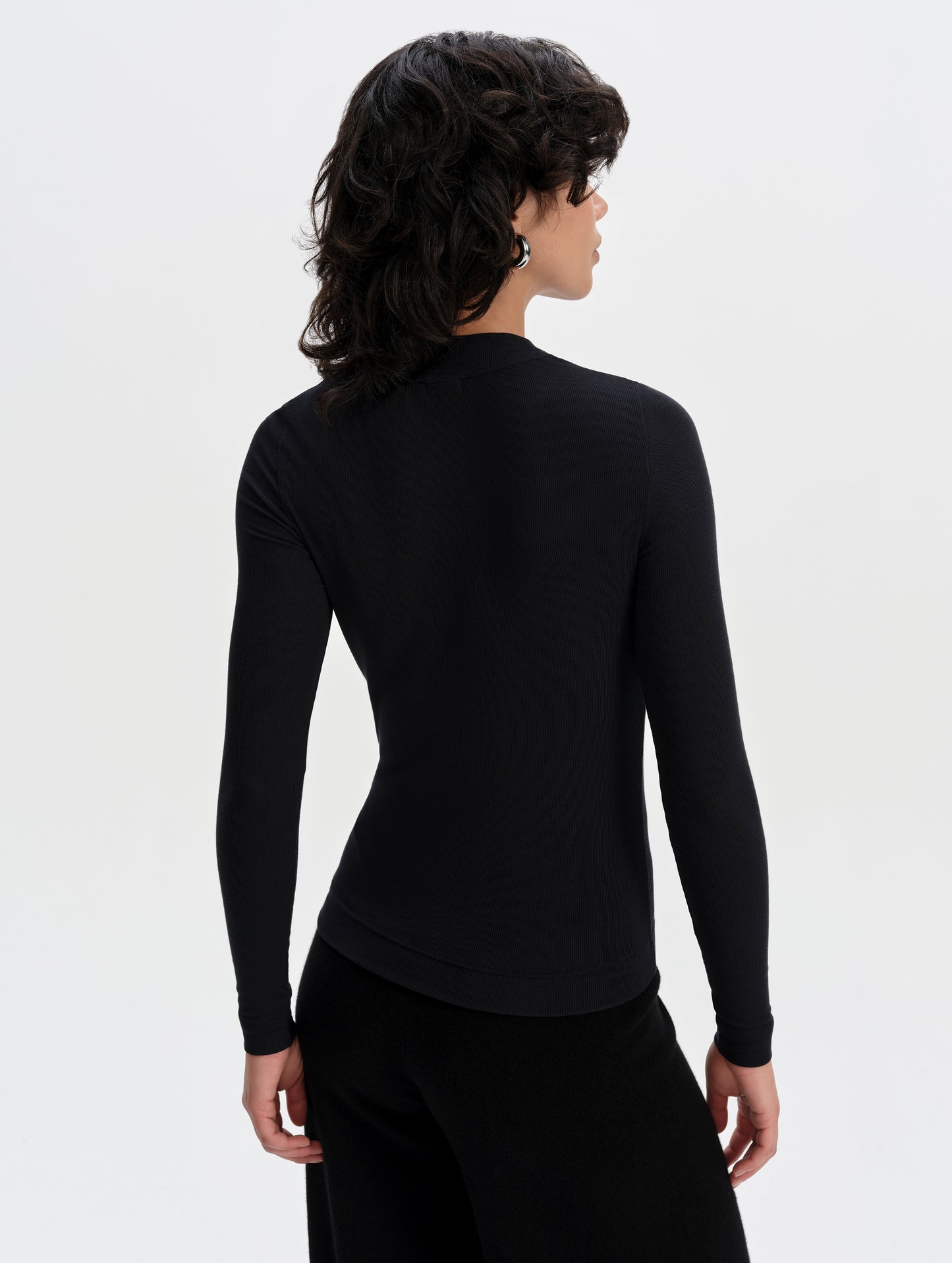 Rear upper-body view of woman wearing the Legacy Long-Sleeve Henley in Onyx Black from AETHER Apparel.