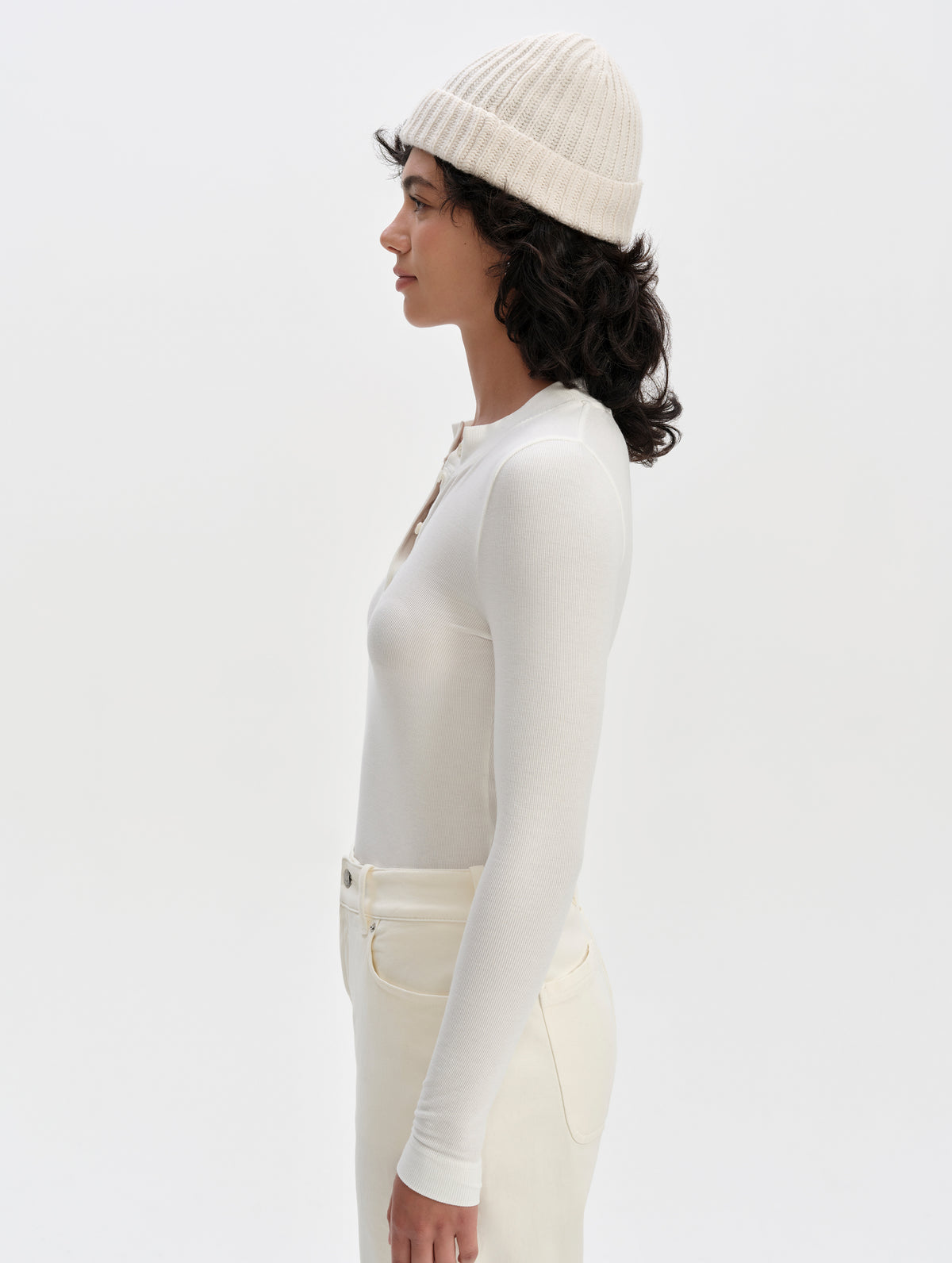Side profile upper-body view of woman wearing the Legacy Long-Sleeve Henley in Winter White from AETHER Apparel.